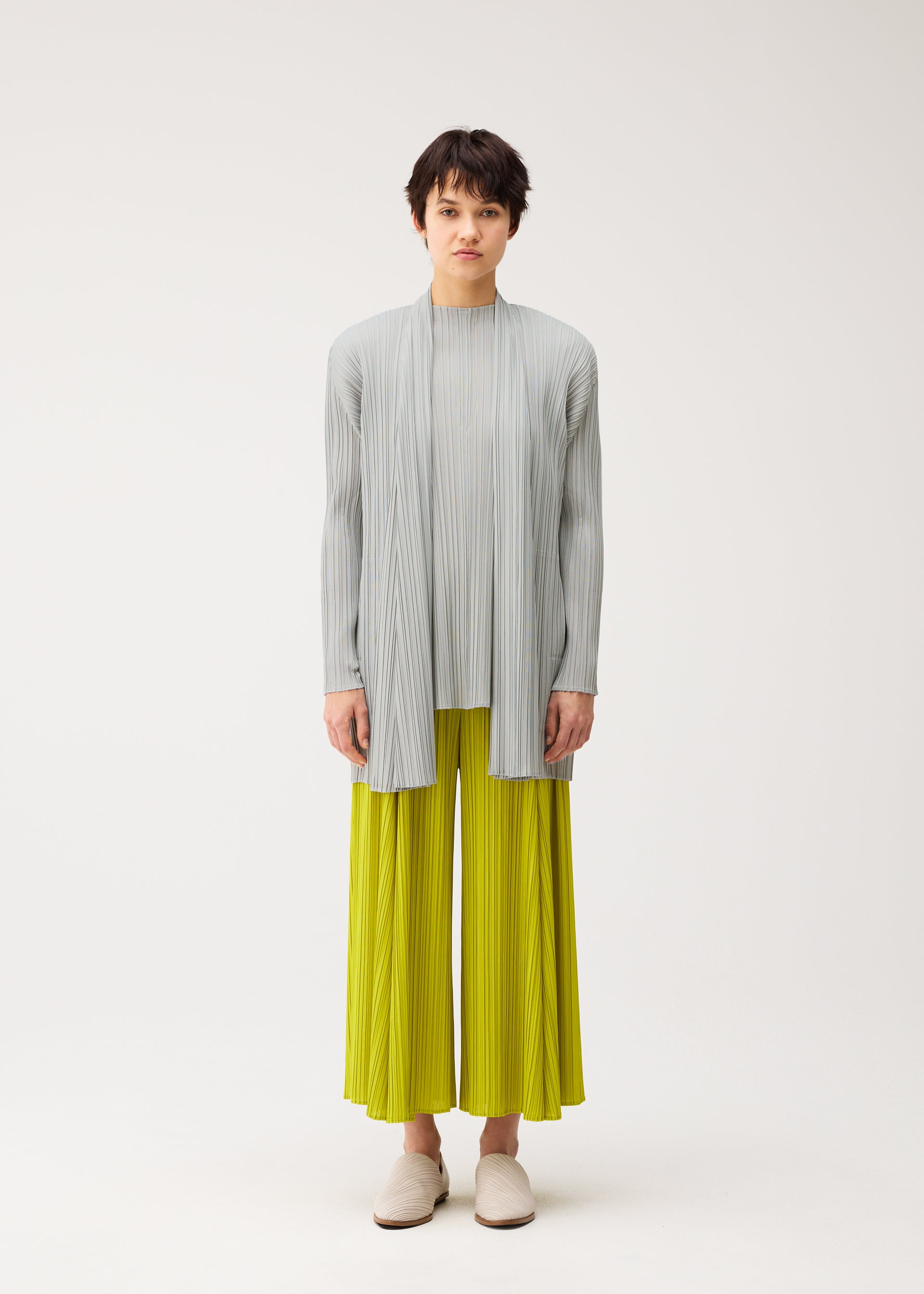 A model wears the PLEATS PLEASE ISSEY MIYAKE MELLOW PLEATS cardigan.