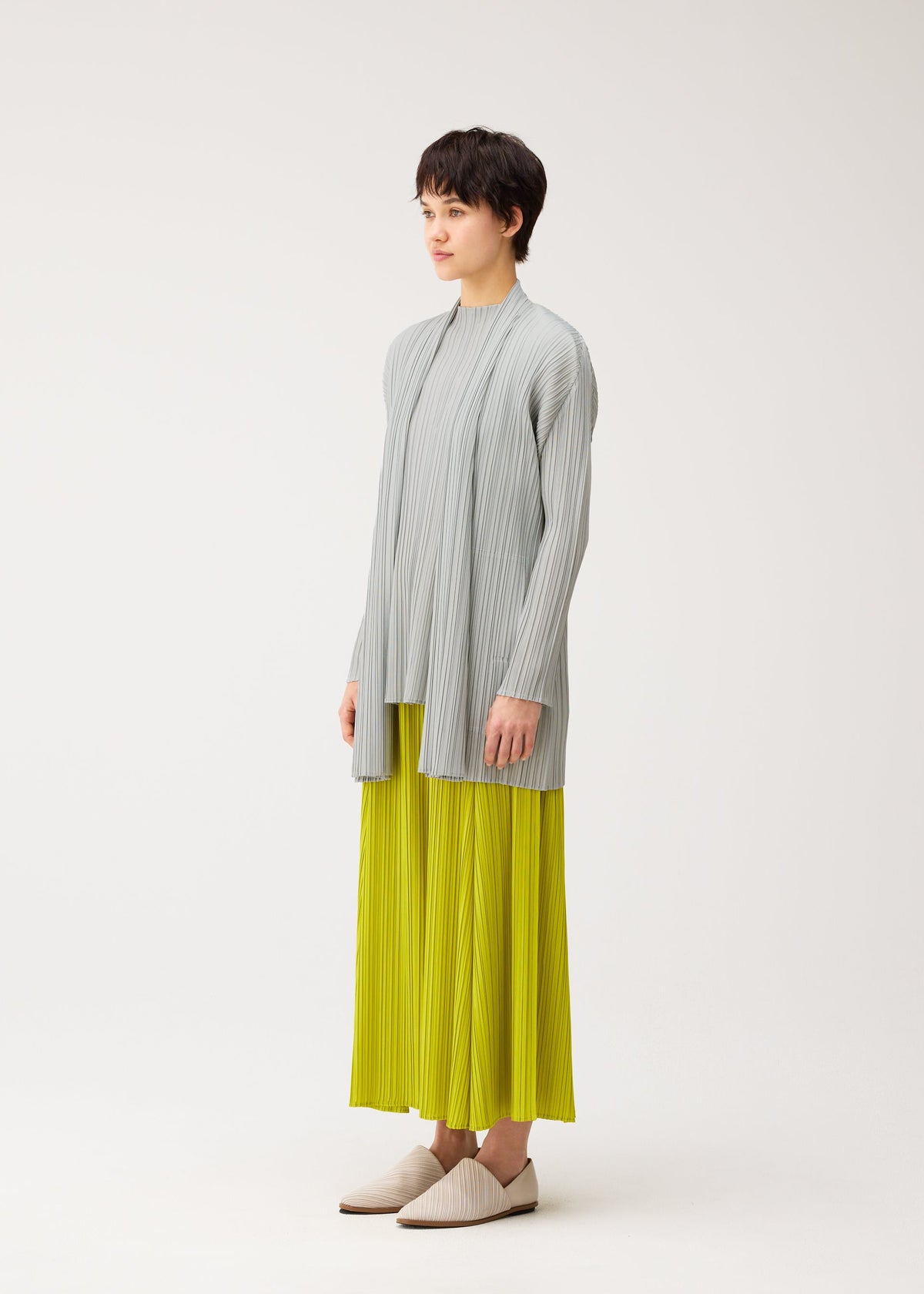 A model wears the PLEATS PLEASE ISSEY MIYAKE MELLOW PLEATS cardigan.