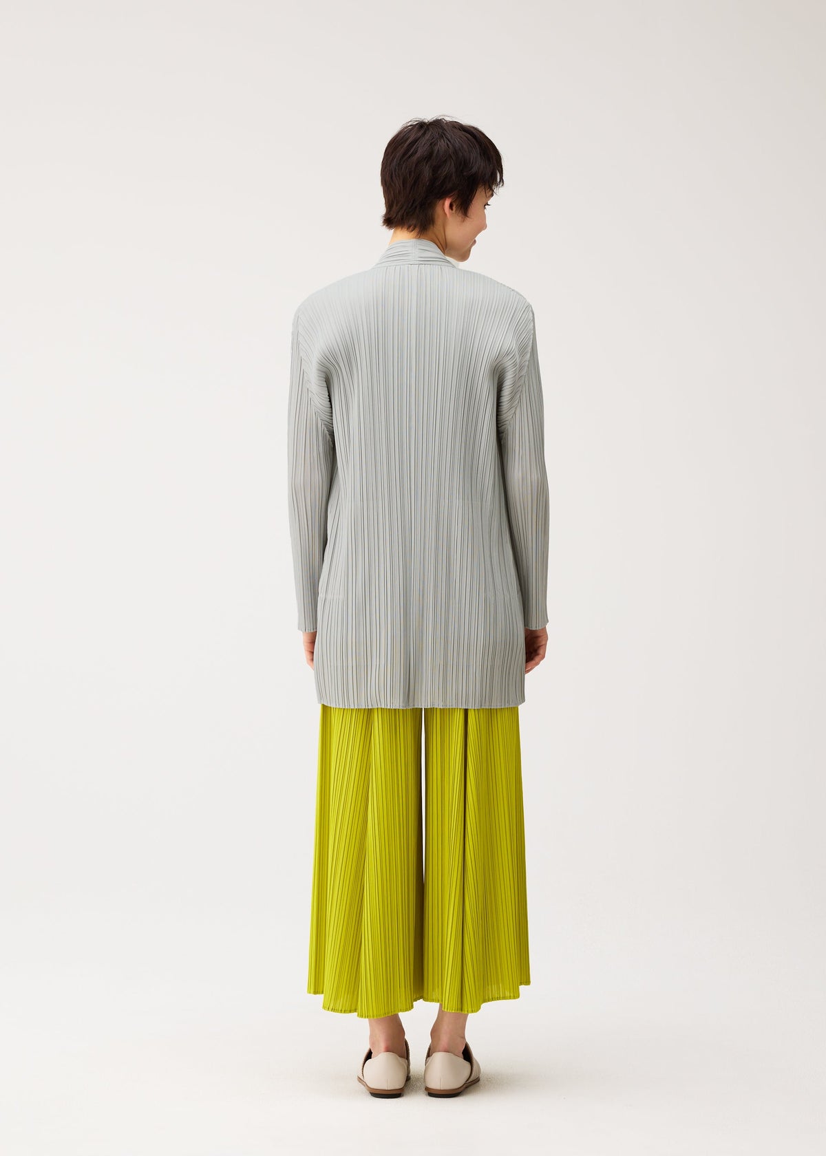 A model wears the PLEATS PLEASE ISSEY MIYAKE MELLOW PLEATS cardigan.