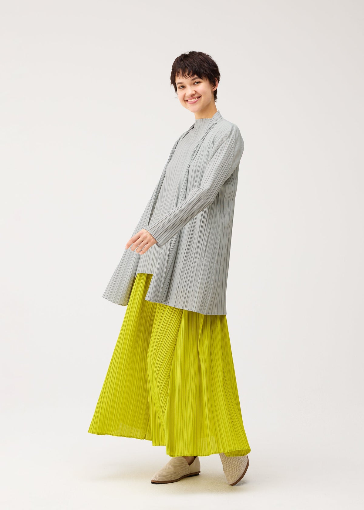 A model wears the PLEATS PLEASE ISSEY MIYAKE MELLOW PLEATS cardigan.