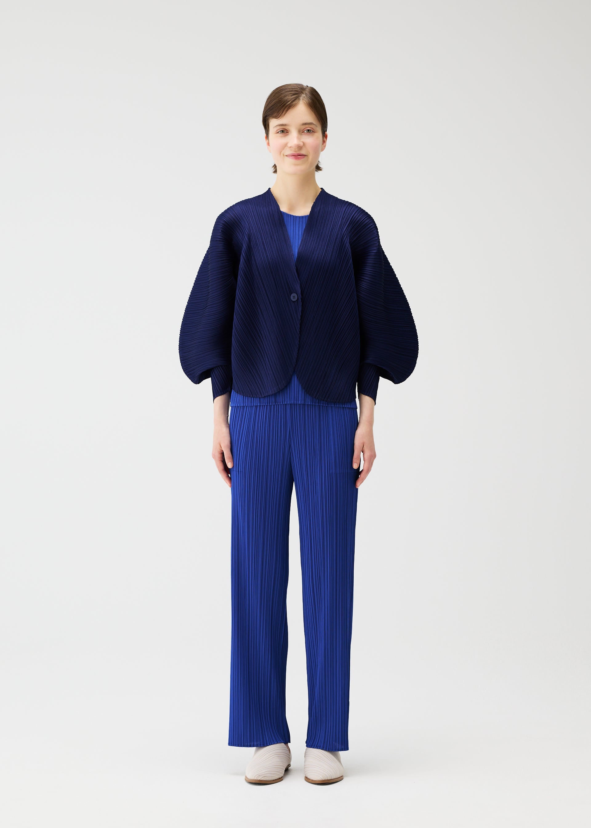 A model wears the PLEATS PLEASE ISSEY MIYAKE COAST cardigan.