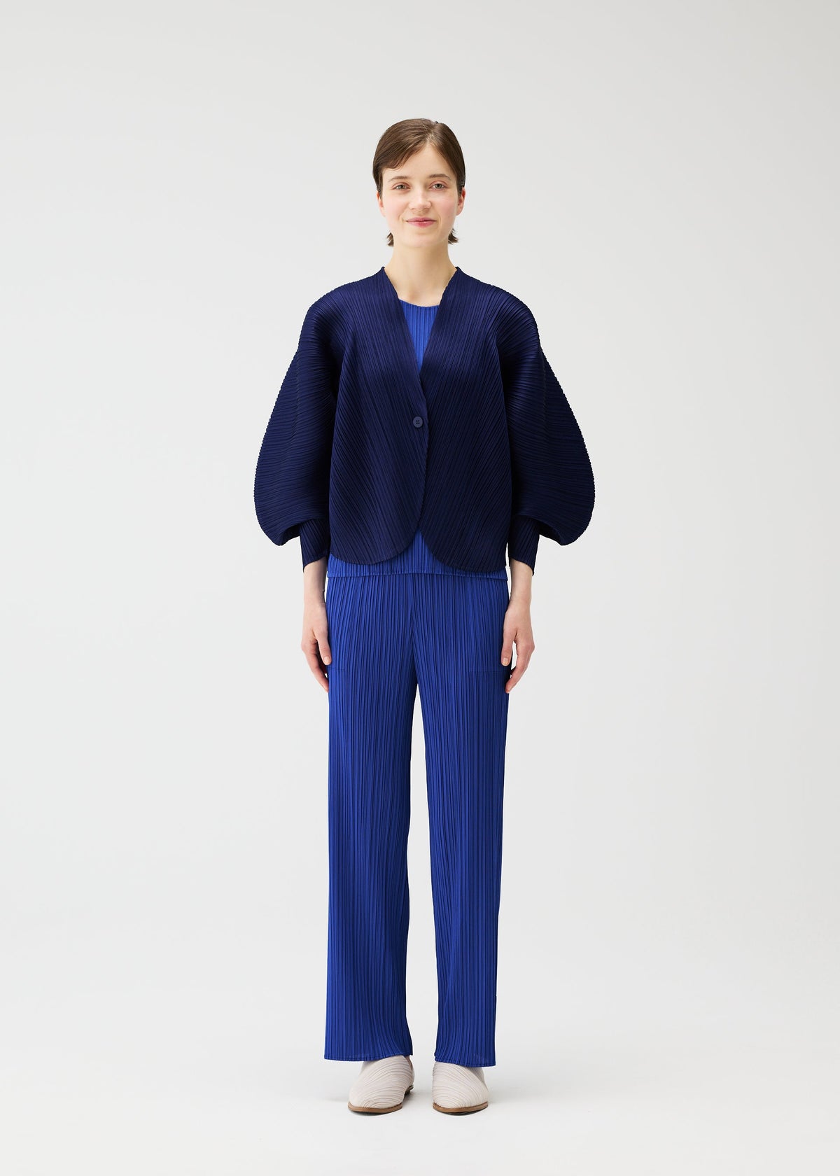 A model wears the PLEATS PLEASE ISSEY MIYAKE COAST cardigan.