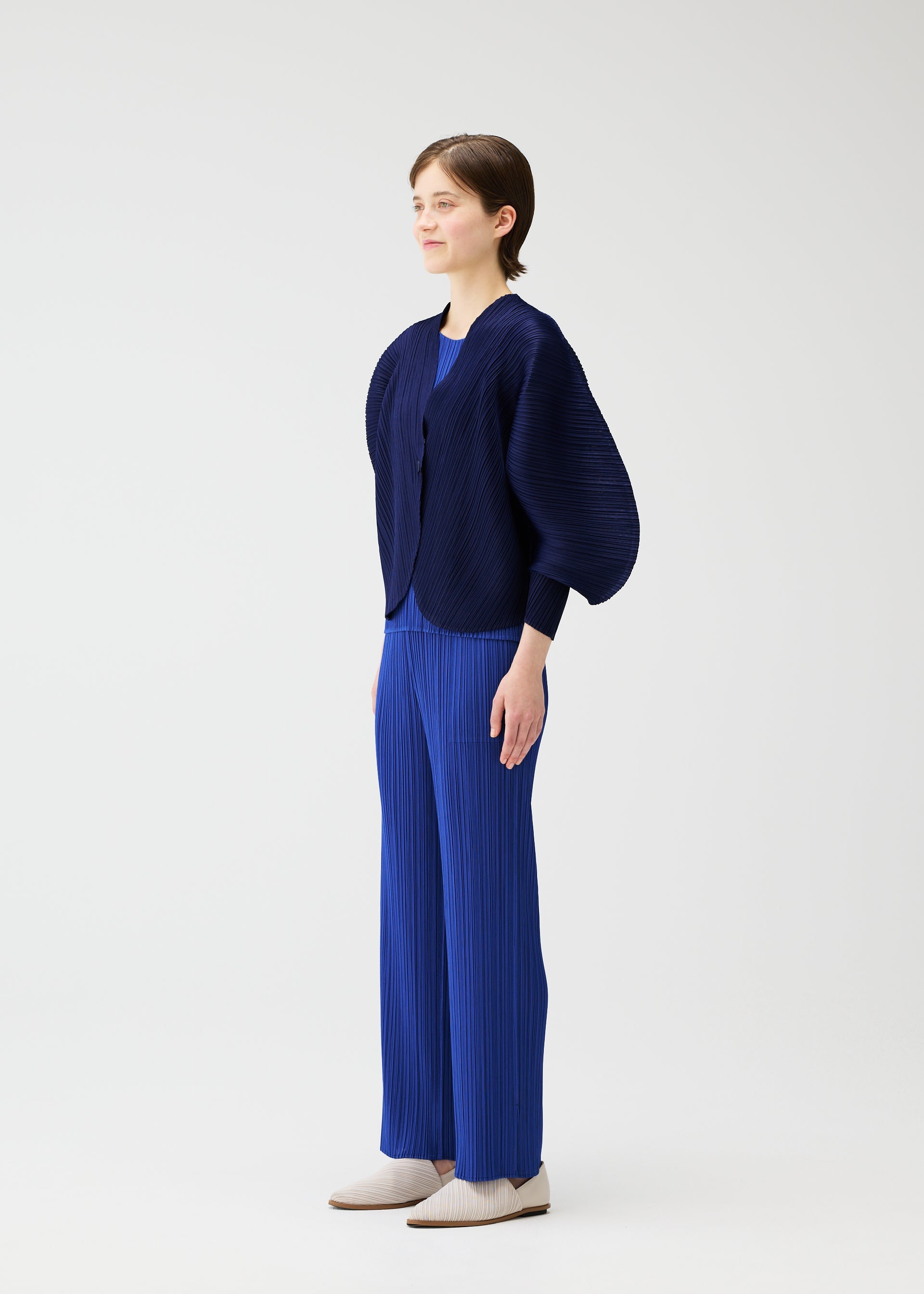 A model wears the PLEATS PLEASE ISSEY MIYAKE COAST cardigan.