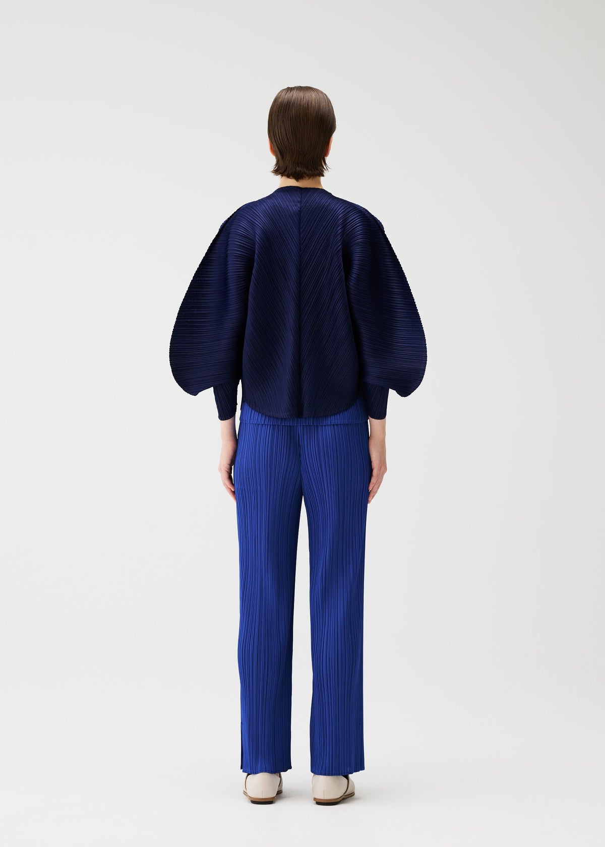 A model wears the PLEATS PLEASE ISSEY MIYAKE COAST cardigan.