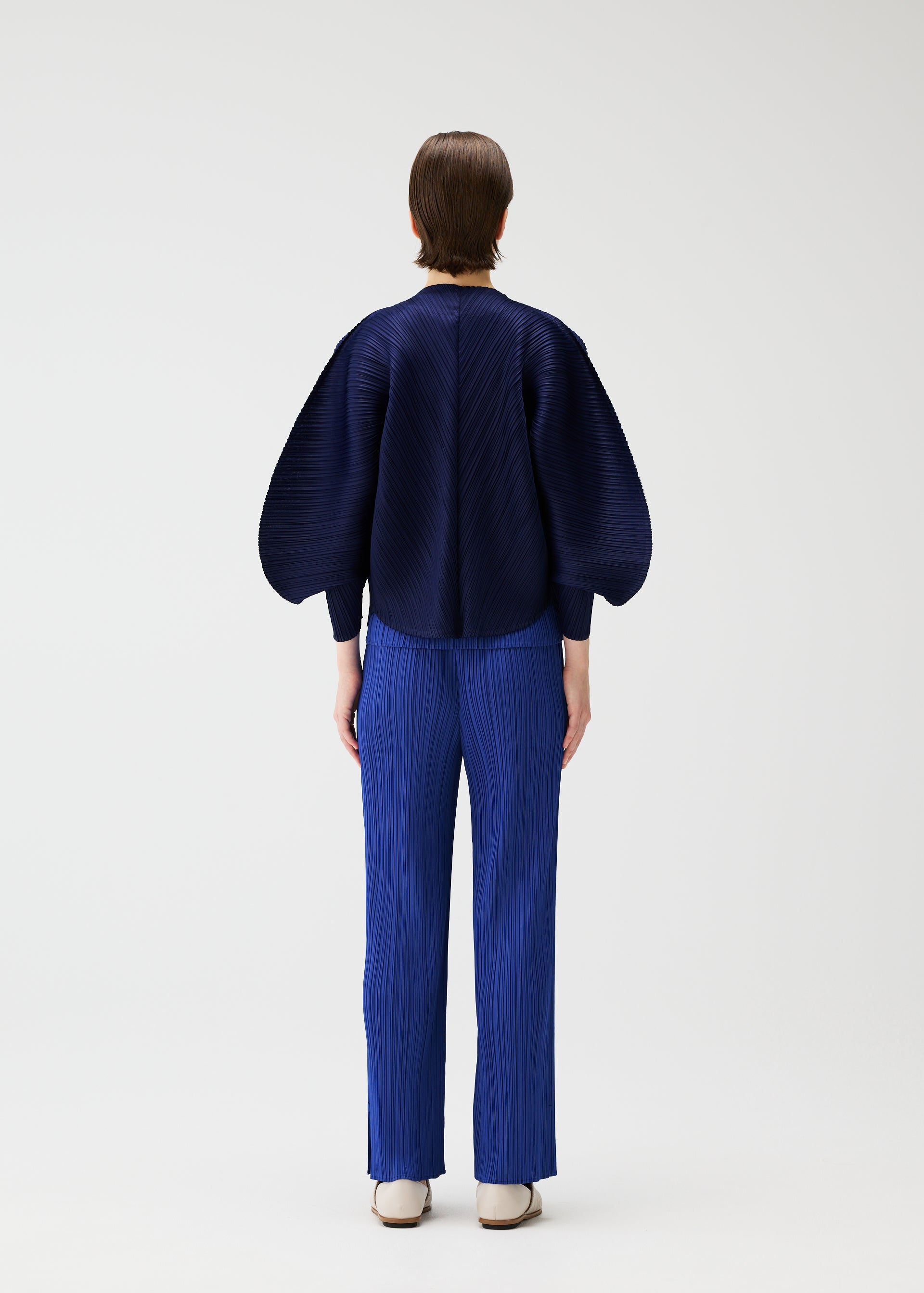 A model wears the PLEATS PLEASE ISSEY MIYAKE COAST cardigan.