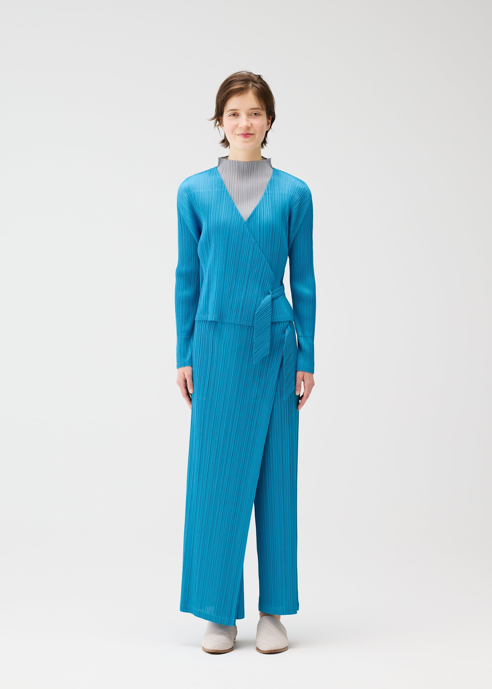 A model wears the PLEATS PLEASE ISSEY MIYAKE FACADE cardigan.