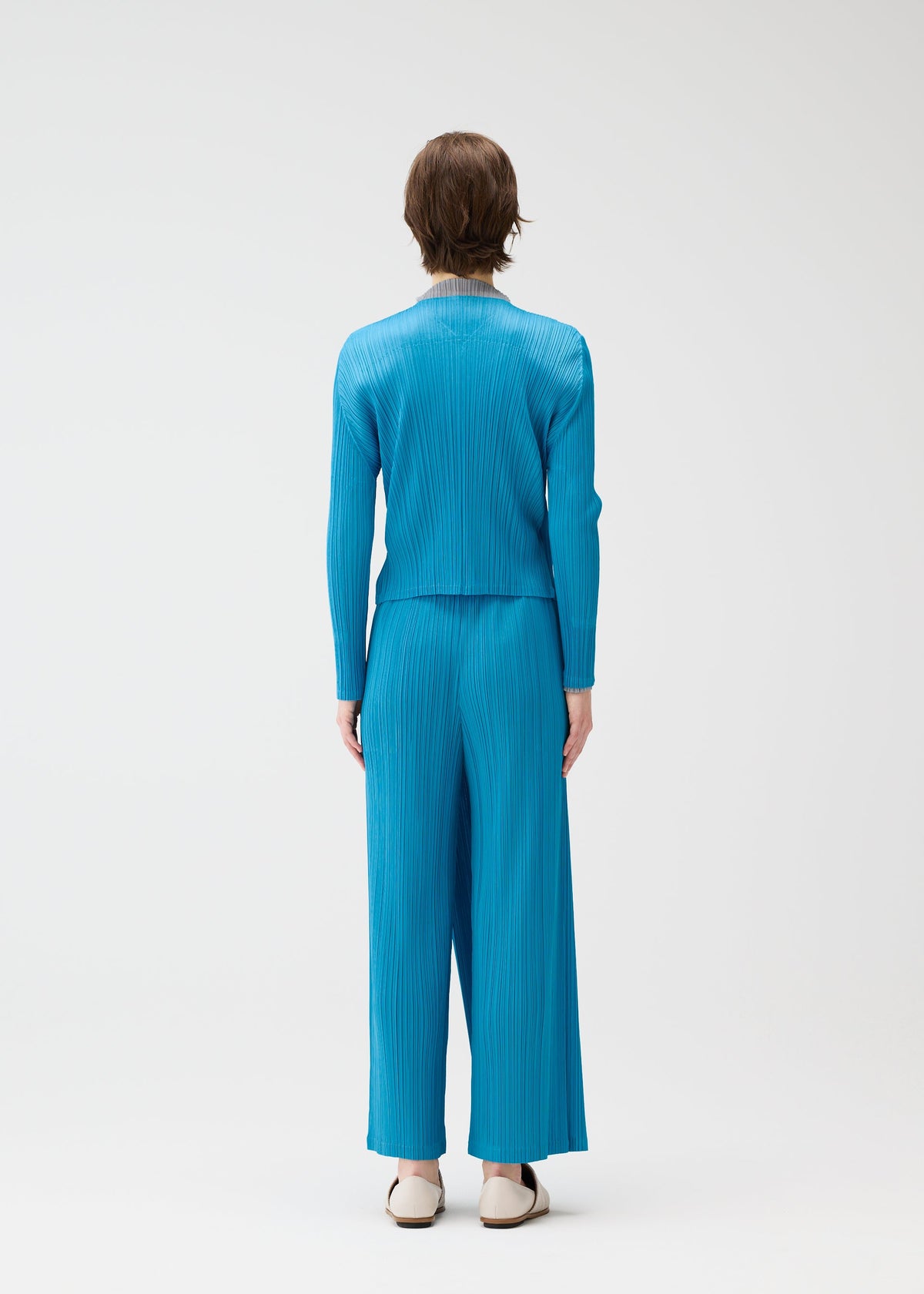 A model wears the PLEATS PLEASE ISSEY MIYAKE FACADE cardigan.