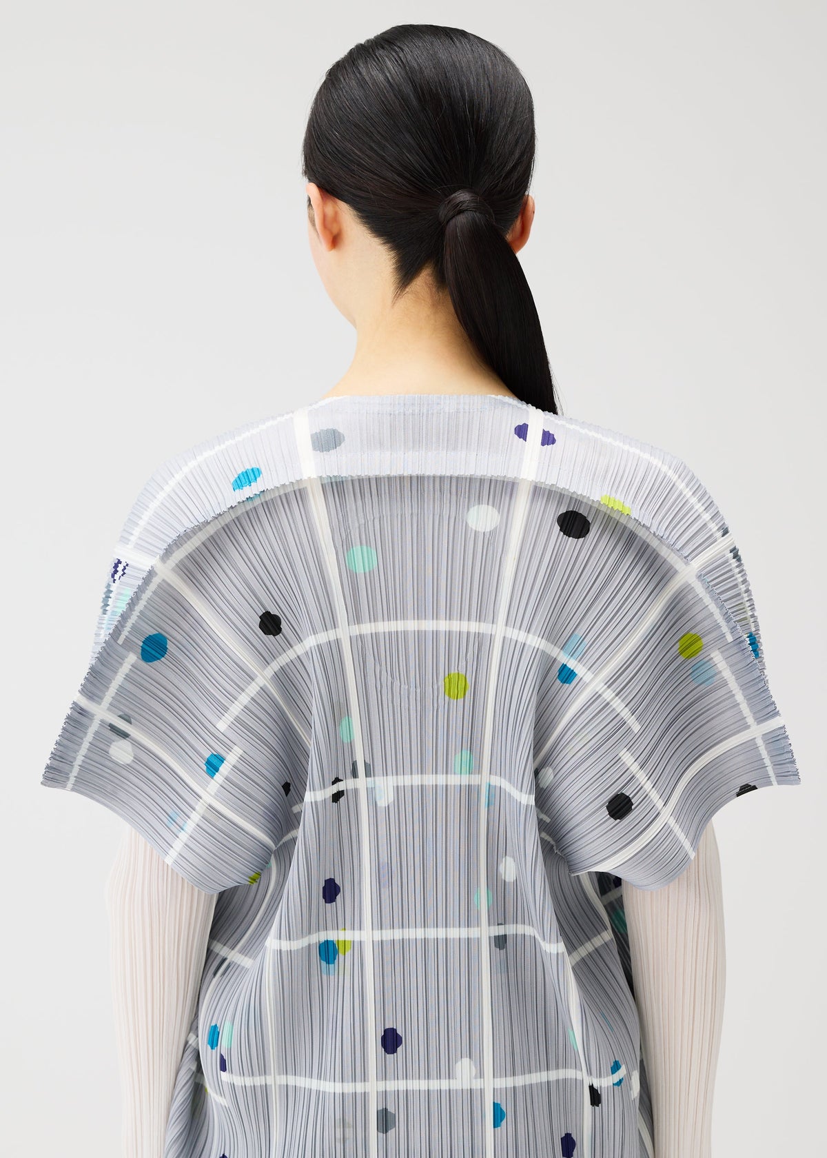 A model wears the PLEATS PLEASE ISSEY MIYAKE CROSSING DOTS dress.