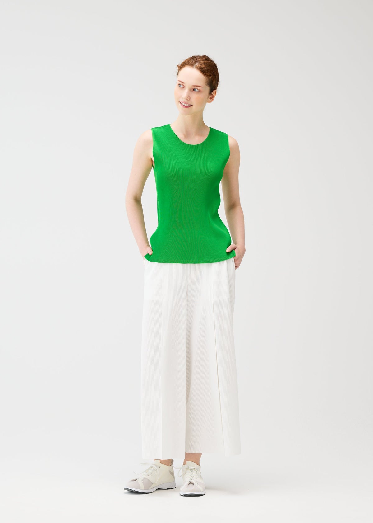 A model wears the PLEATS PLEASE ISSEY MIYAKE A POC BOTTOMS trousers.