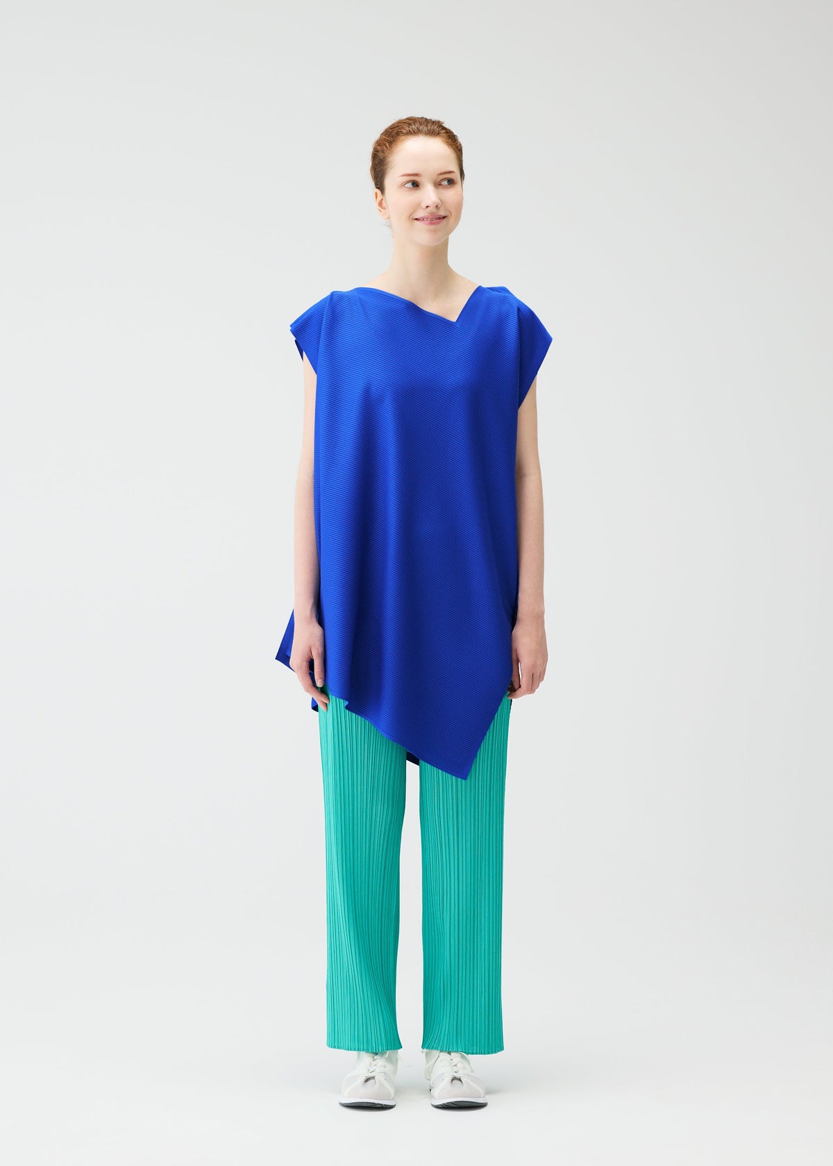 A model wears the PLEATS PLEASE ISSEY MIYAKE A POC SEA GLASS tunic.