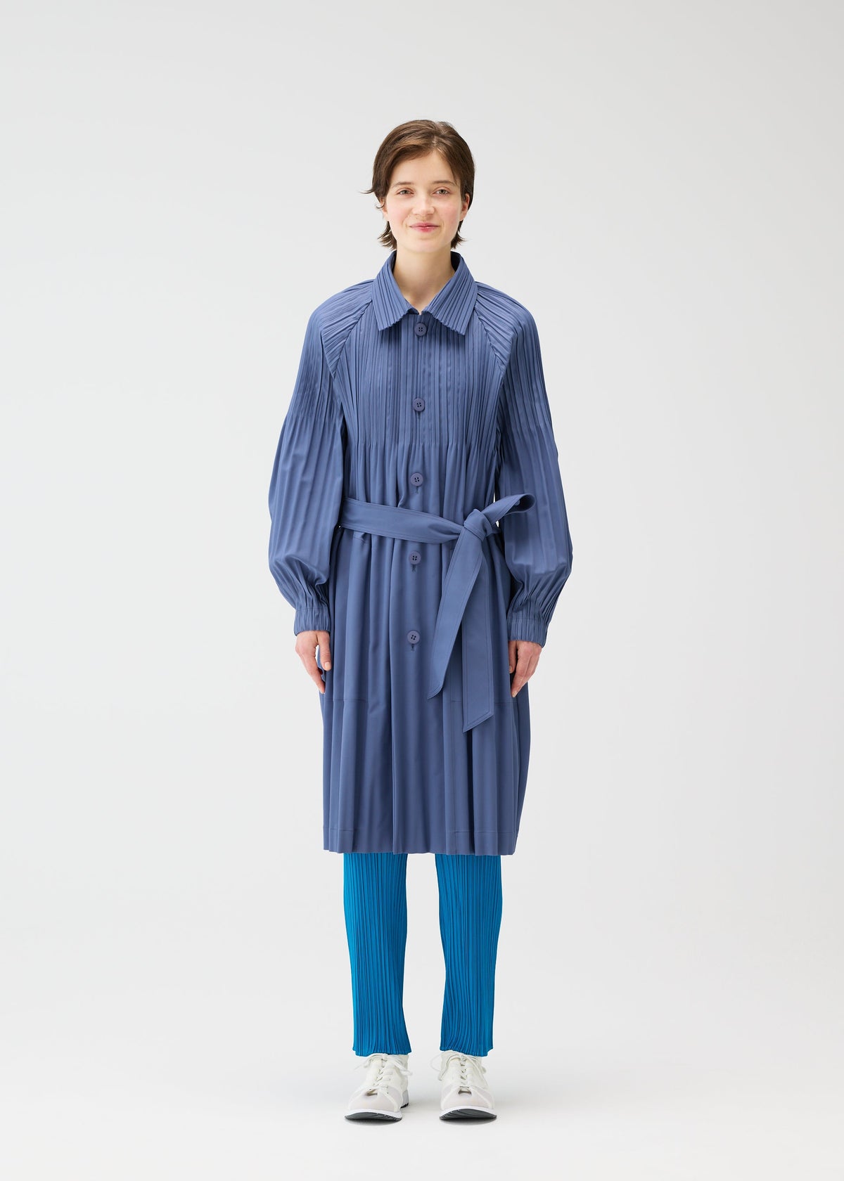 A model wears the PLEATS PLEASE ISSEY MIYAKE SMOOTH COAT coat.