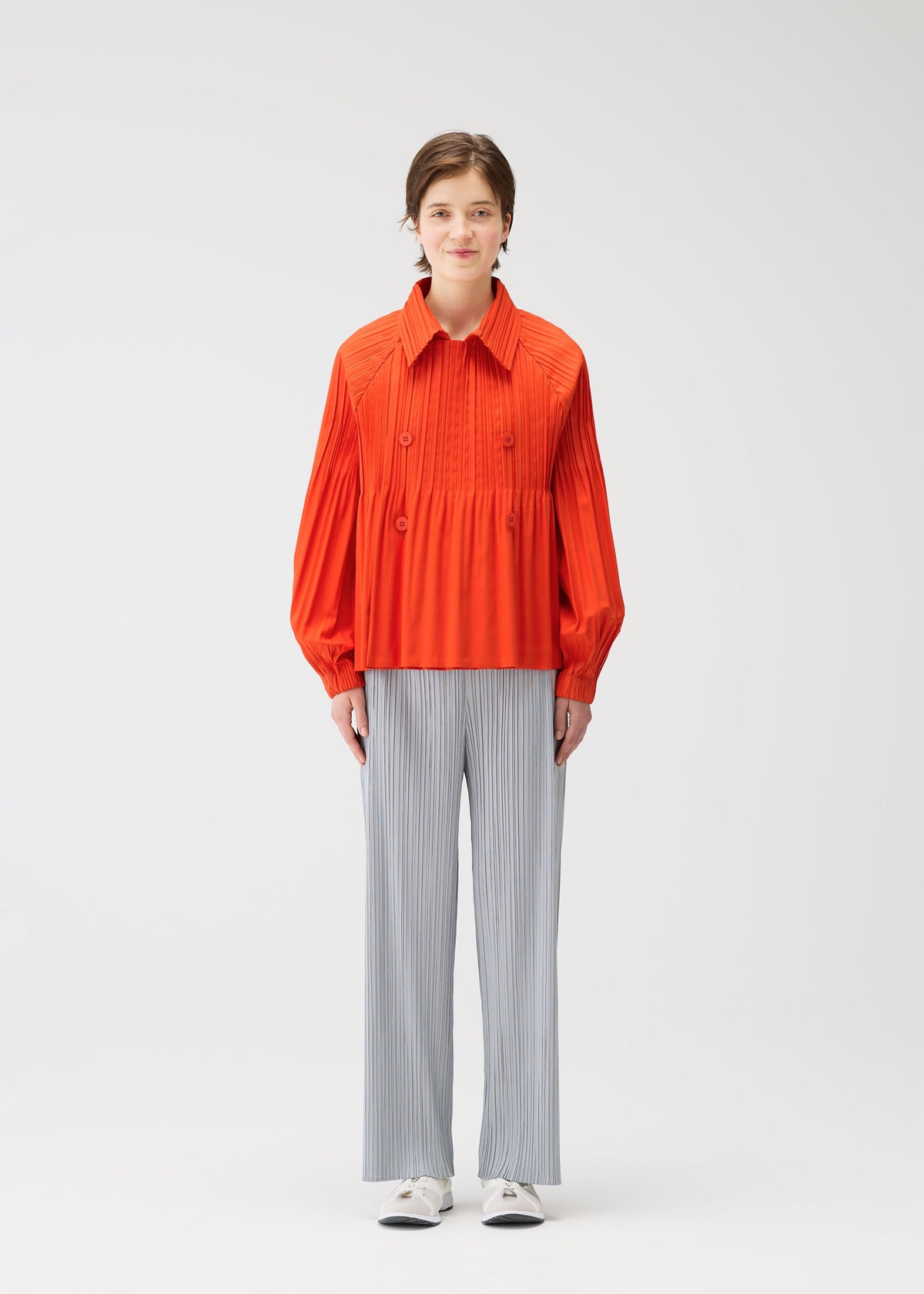 A model wears the PLEATS PLEASE ISSEY MIYAKE SMOOTH COAT coat.