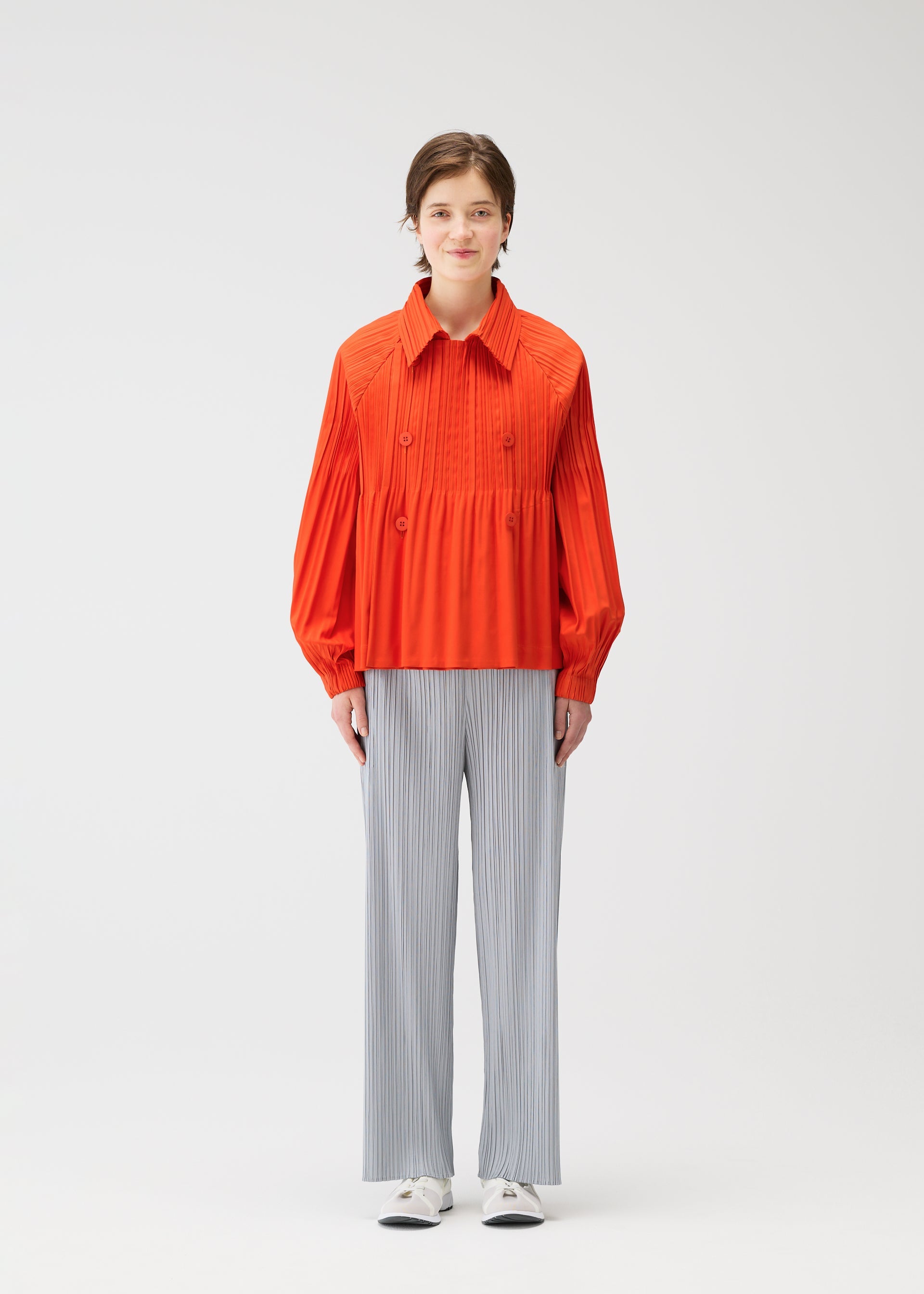 A model wears the PLEATS PLEASE ISSEY MIYAKE SMOOTH COAT coat.
