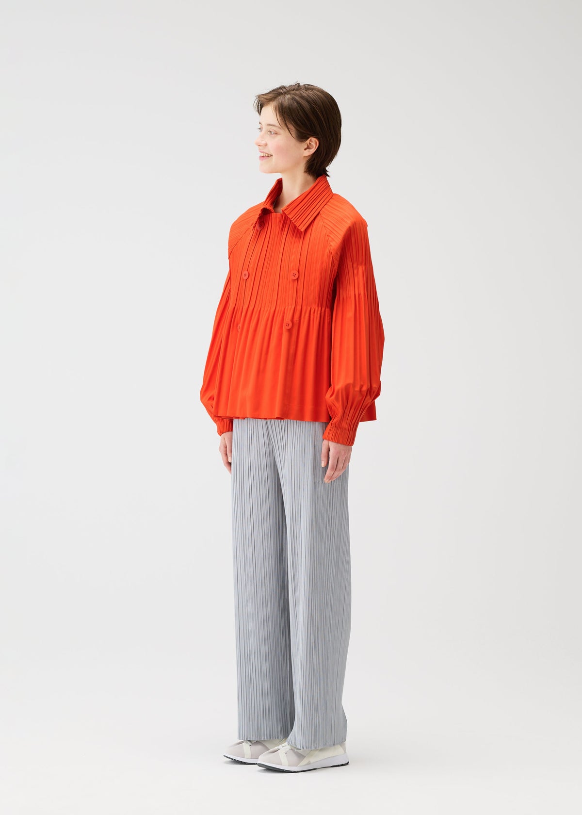 A model wears the PLEATS PLEASE ISSEY MIYAKE SMOOTH COAT coat.