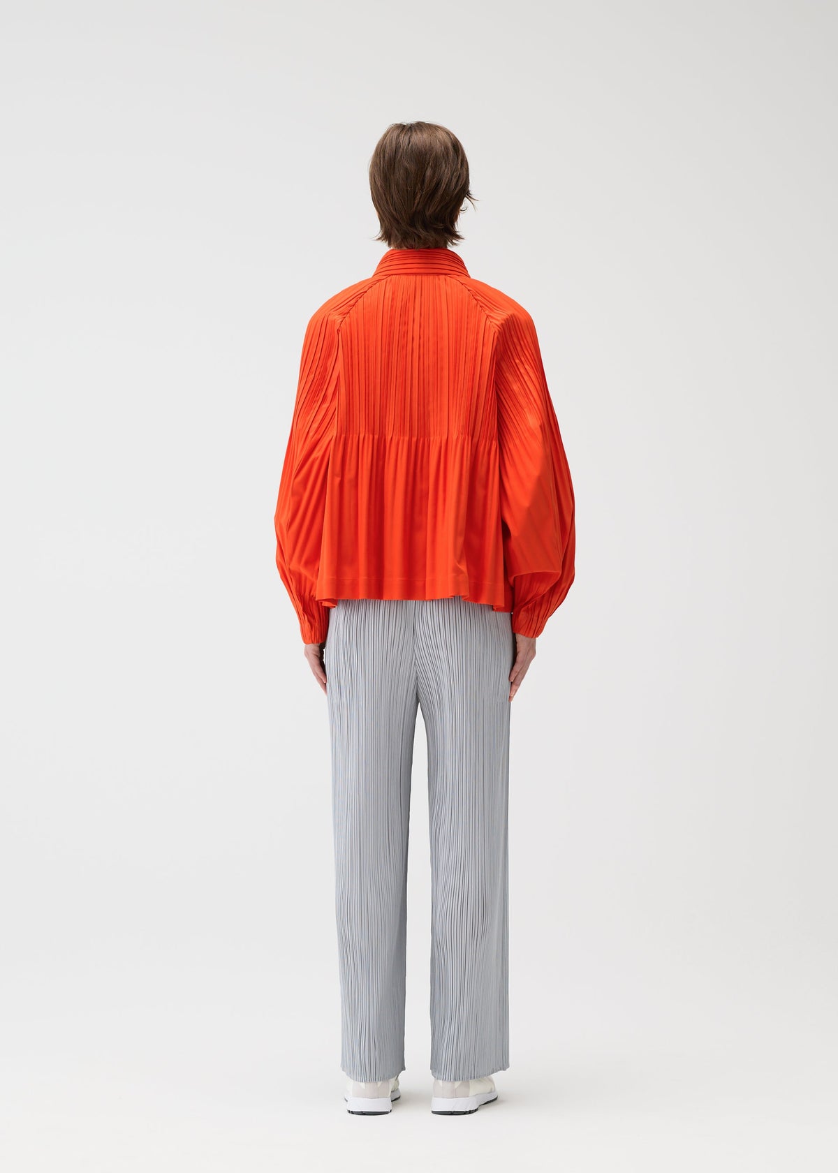 A model wears the PLEATS PLEASE ISSEY MIYAKE SMOOTH COAT coat.