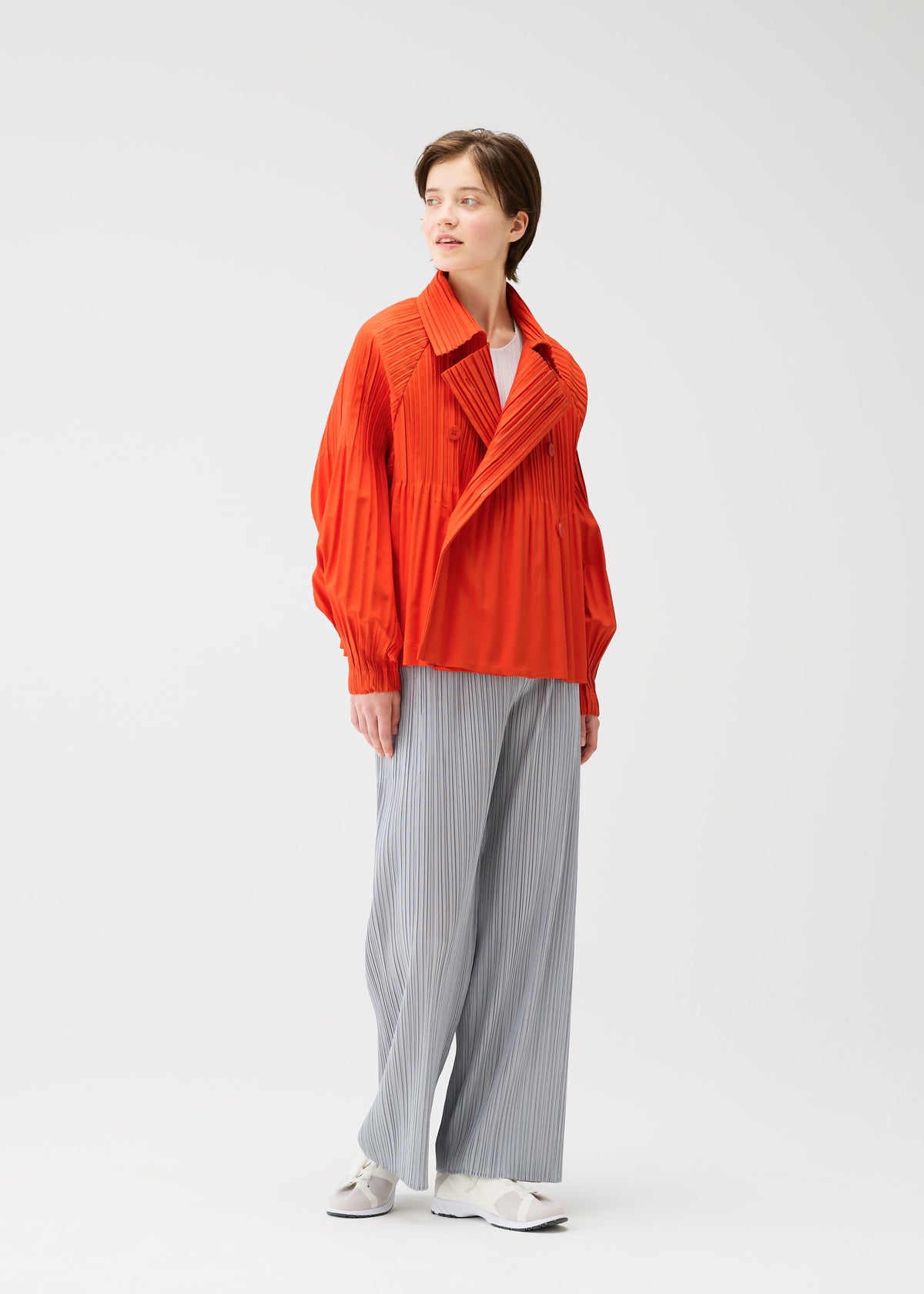 A model wears the PLEATS PLEASE ISSEY MIYAKE SMOOTH COAT coat.