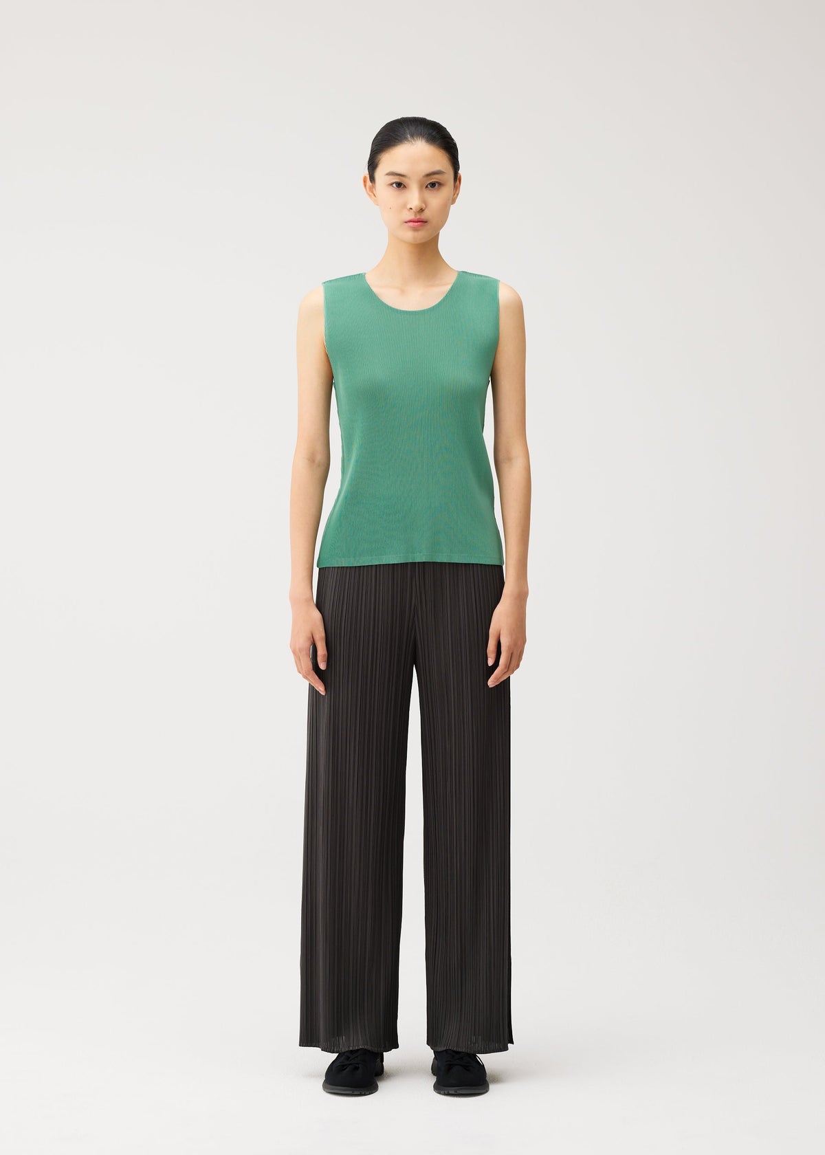 A model wears the PLEATS PLEASE ISSEY MIYAKE MIST AUGUST mist-august-top-greyish-green.