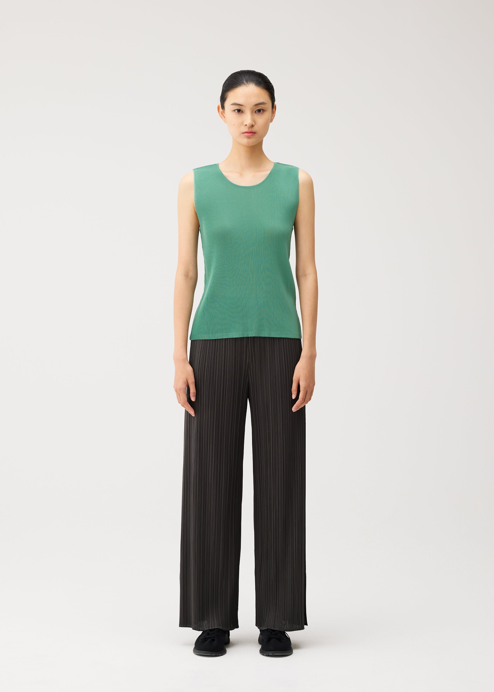 A model wears the PLEATS PLEASE ISSEY MIYAKE MIST AUGUST mist-august-top-greyish-green.