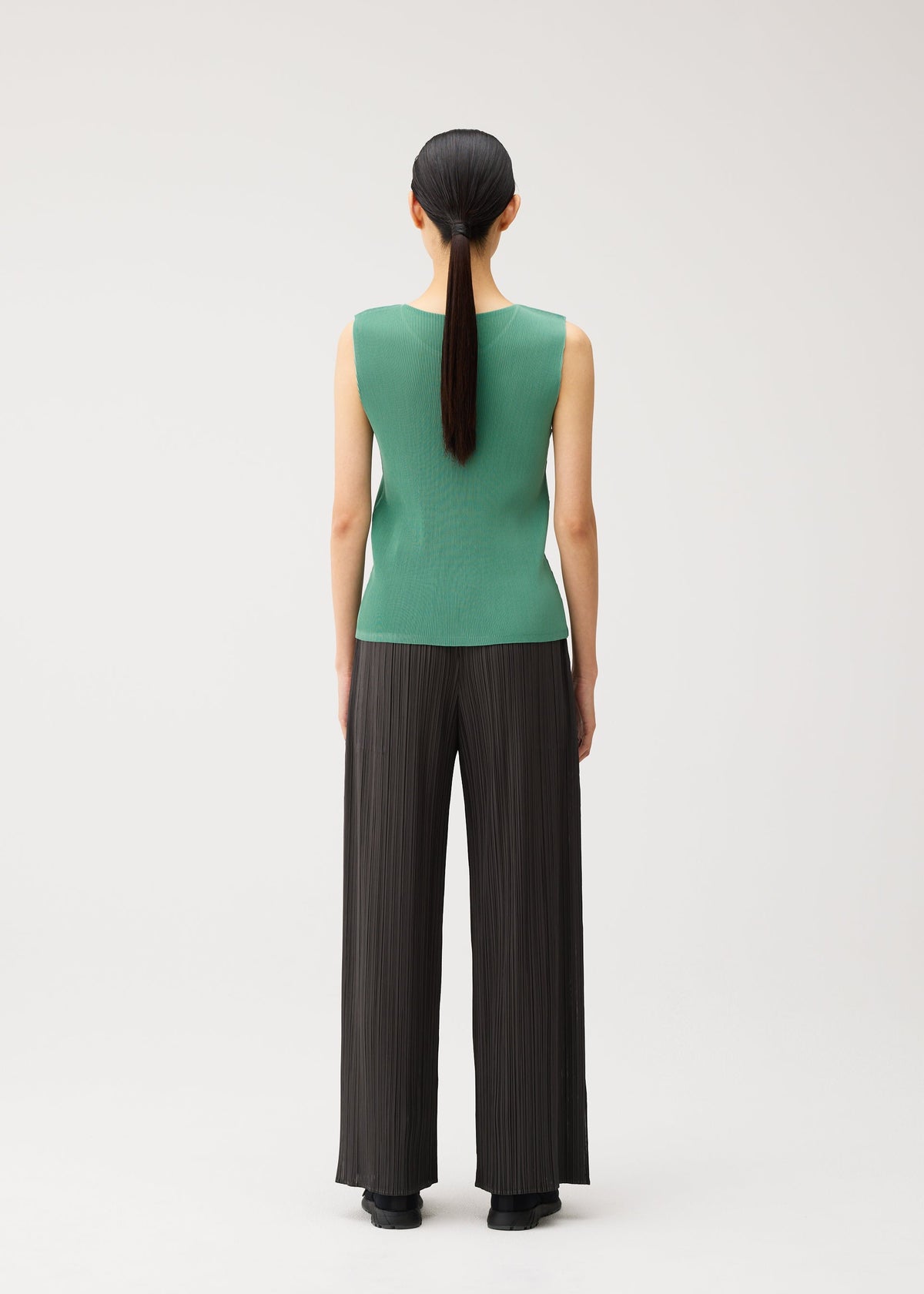 A model wears the PLEATS PLEASE ISSEY MIYAKE MIST AUGUST mist-august-top-greyish-green.
