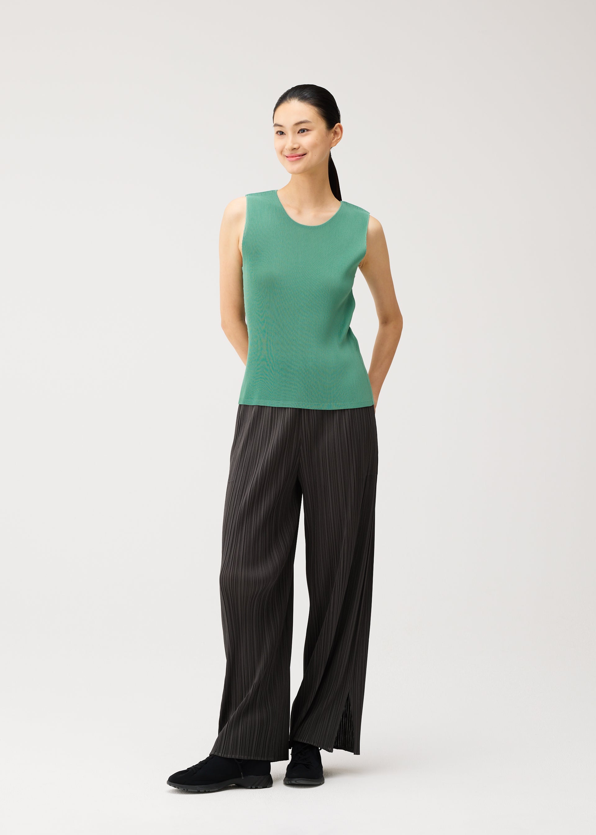 A model wears the PLEATS PLEASE ISSEY MIYAKE MIST AUGUST mist-august-top-greyish-green.