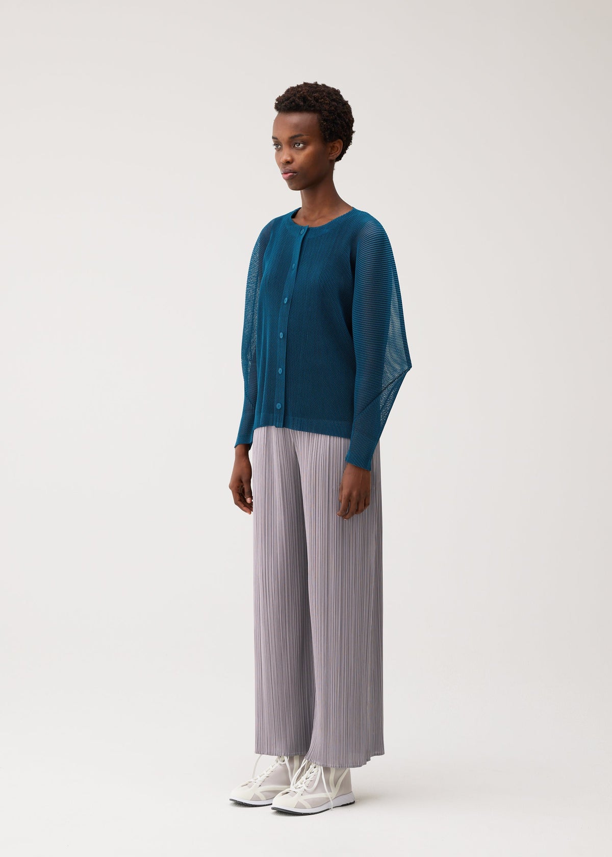 A model wears the PLEATS PLEASE ISSEY MIYAKE TATAMI AUGUST tatami-august-cardigan-off-white.