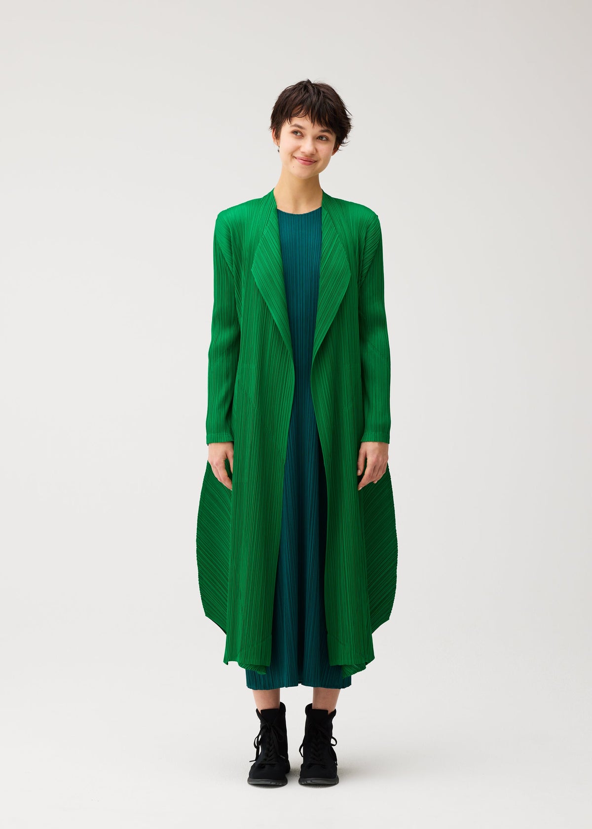 A model wears the PLEATS PLEASE ISSEY MIYAKE MONTHLY COLORS : OCTOBER monthly-colors-october-mid-length-coat-yellow-ochre.