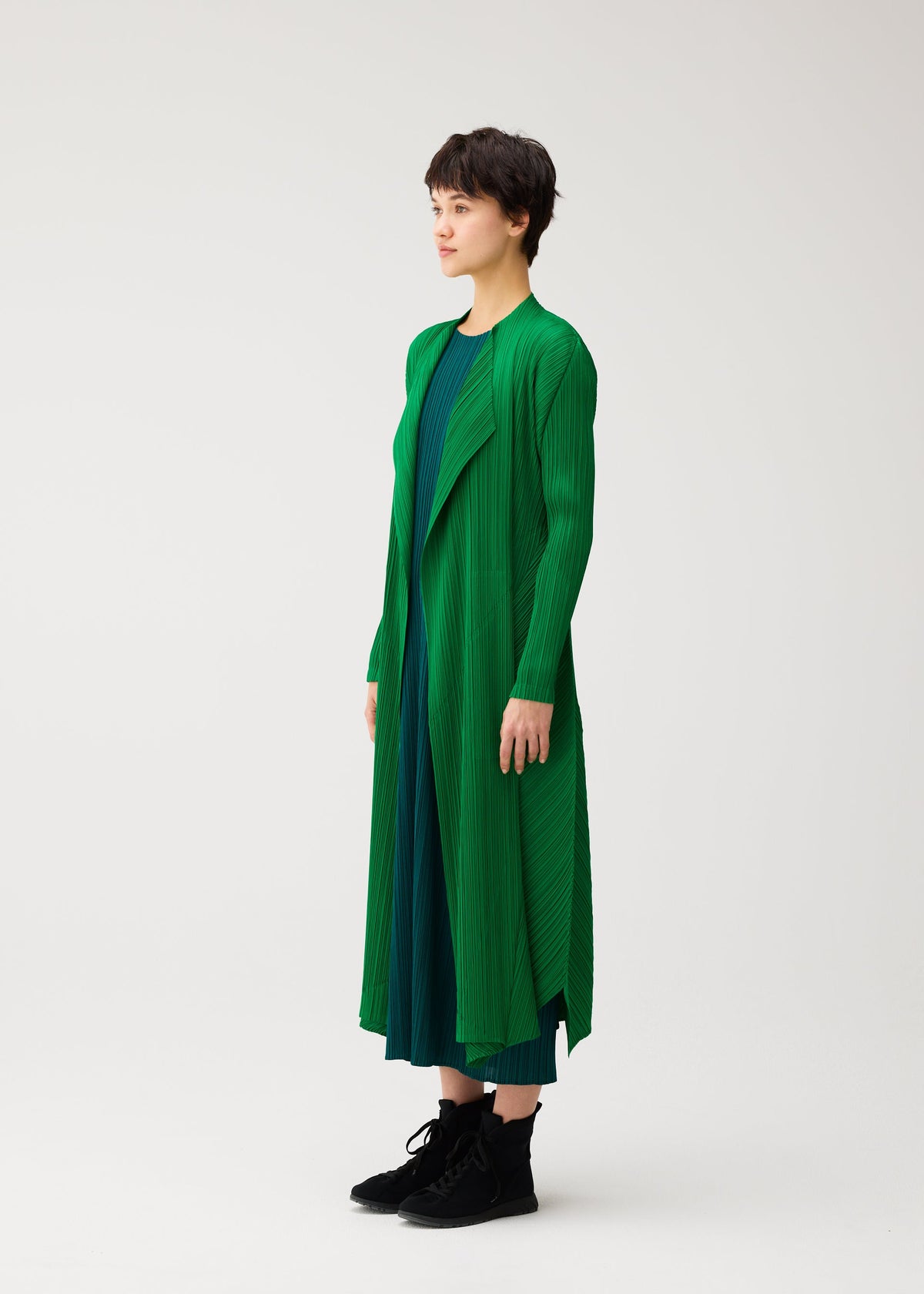 A model wears the PLEATS PLEASE ISSEY MIYAKE MONTHLY COLORS : OCTOBER monthly-colors-october-mid-length-coat-dark-green.