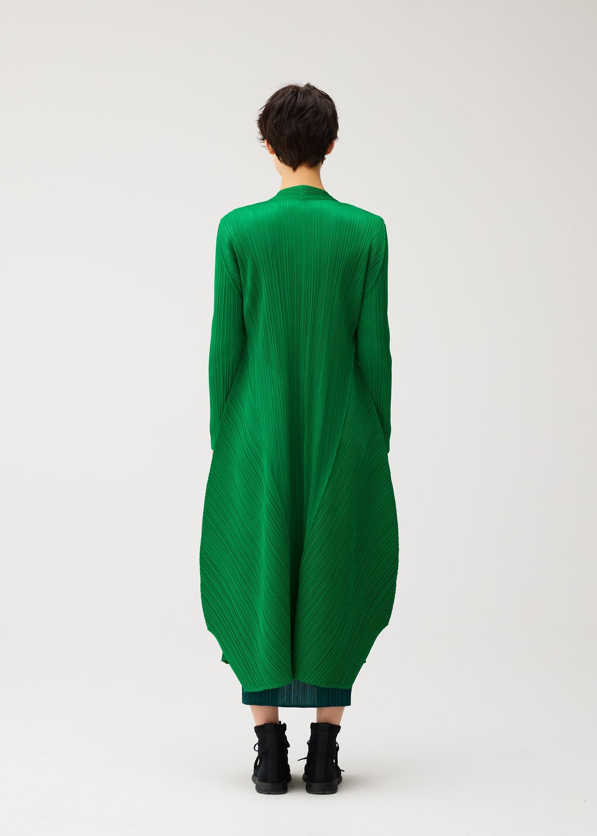 A model wears the PLEATS PLEASE ISSEY MIYAKE MONTHLY COLORS : OCTOBER monthly-colors-october-mid-length-coat-yellow-ochre.