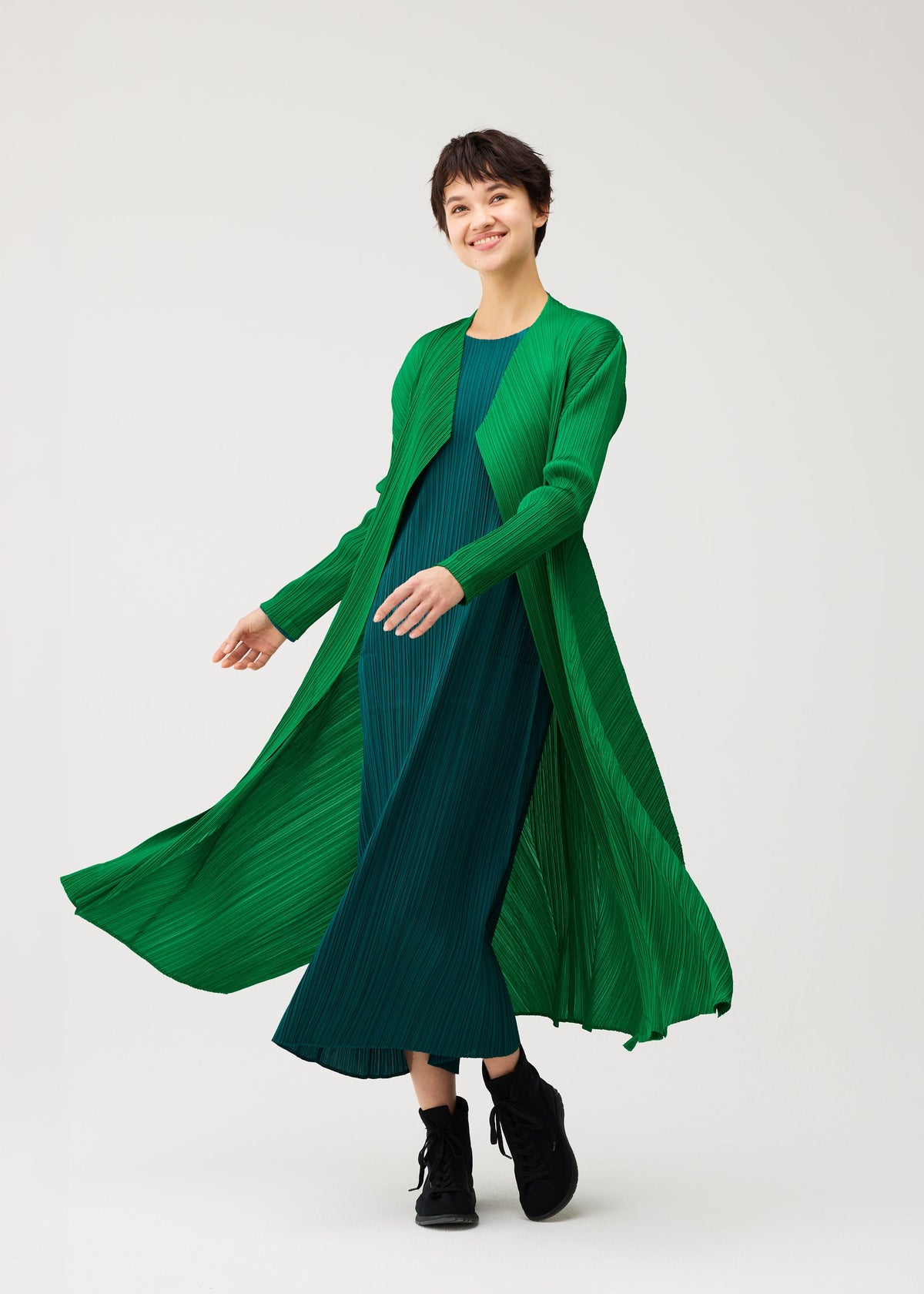 A model wears the PLEATS PLEASE ISSEY MIYAKE MONTHLY COLORS : OCTOBER monthly-colors-october-mid-length-coat-blue-green.