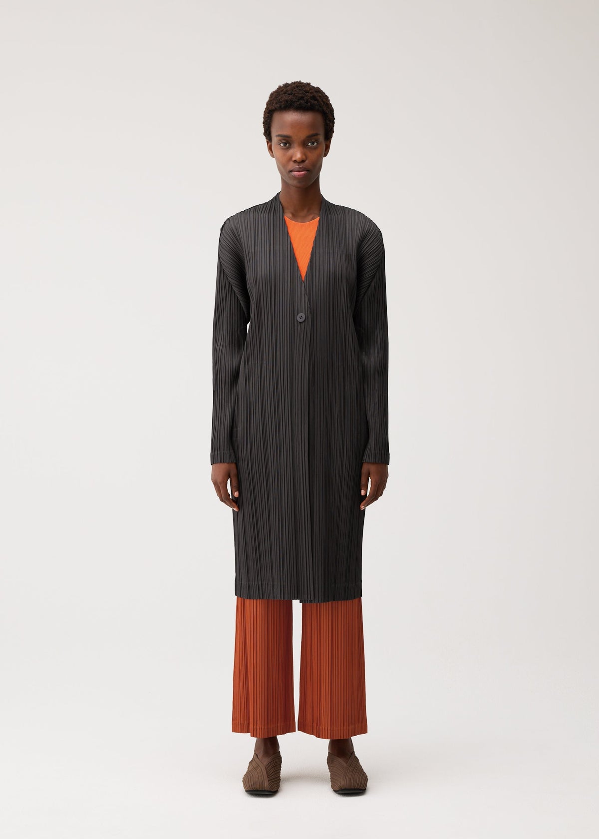 A model wears the PLEATS PLEASE ISSEY MIYAKE PLEATS JACKET pleats-jacket-coat-navy.
