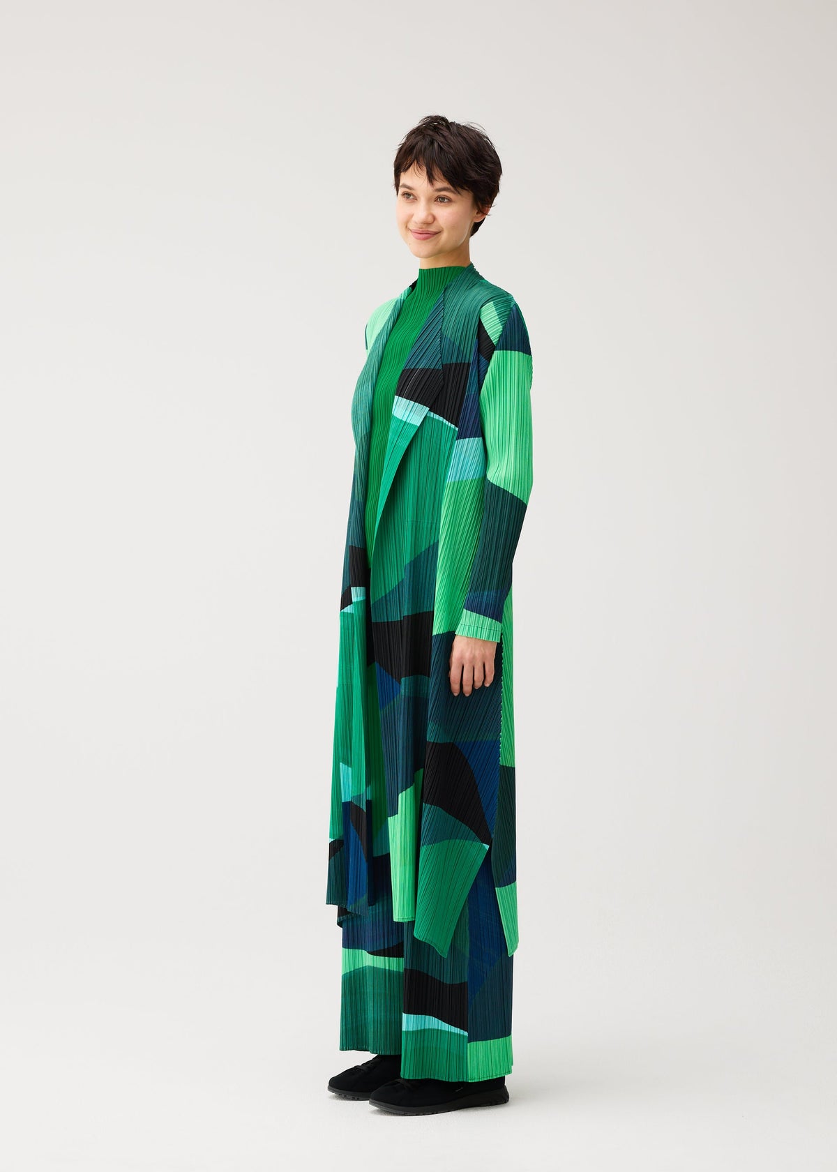 A model wears the PLEATS PLEASE ISSEY MIYAKE ORBIT orbit-coat-green.