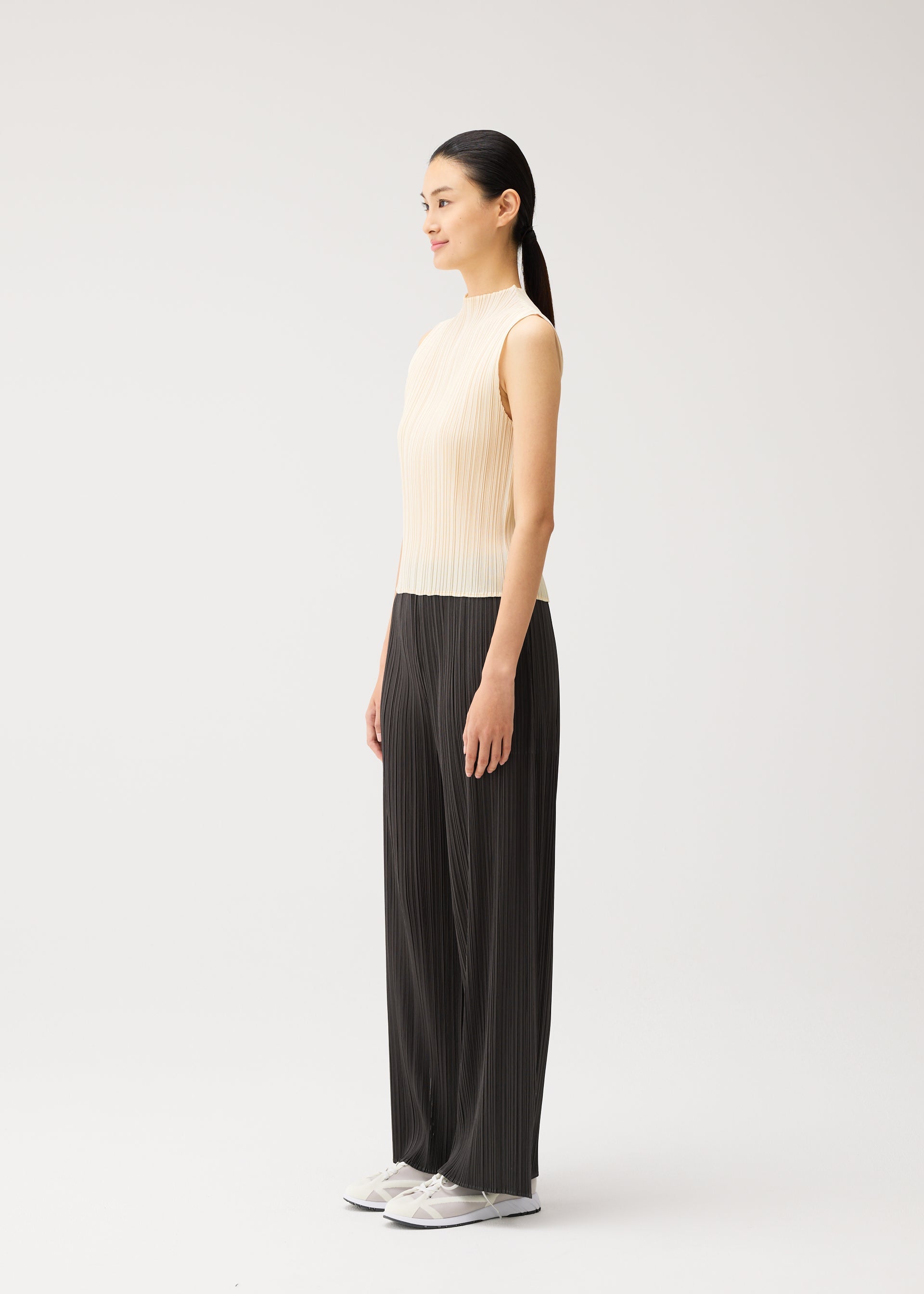 A model wears the PLEATS PLEASE ISSEY MIYAKE MONTHLY COLORS : AUGUST monthly-colors-august-trousers-greyish-green.
