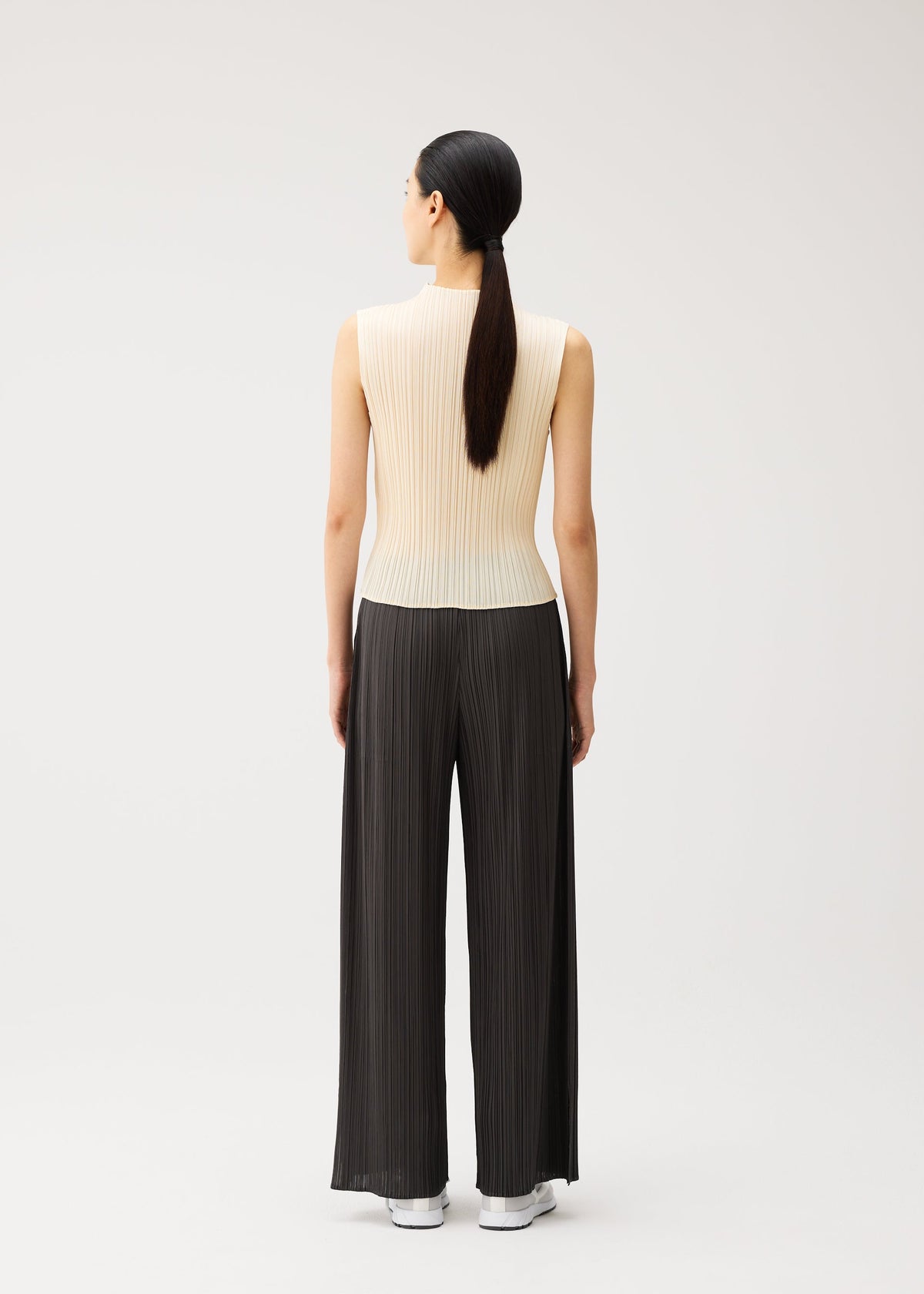 A model wears the PLEATS PLEASE ISSEY MIYAKE MONTHLY COLORS : AUGUST monthly-colors-august-trousers-greyish-green.
