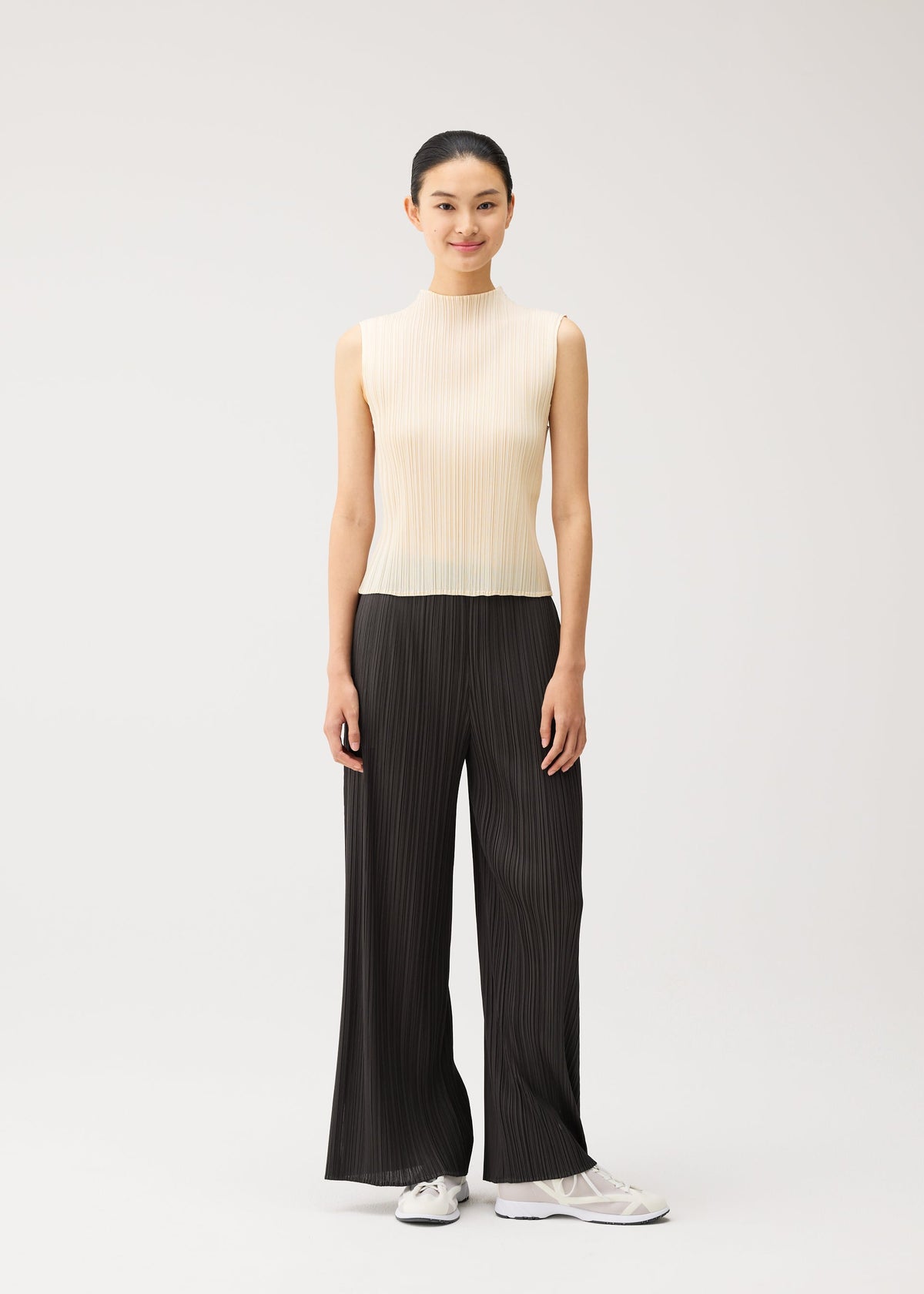 A model wears the PLEATS PLEASE ISSEY MIYAKE MONTHLY COLORS : AUGUST monthly-colors-august-trousers-greyish-green.