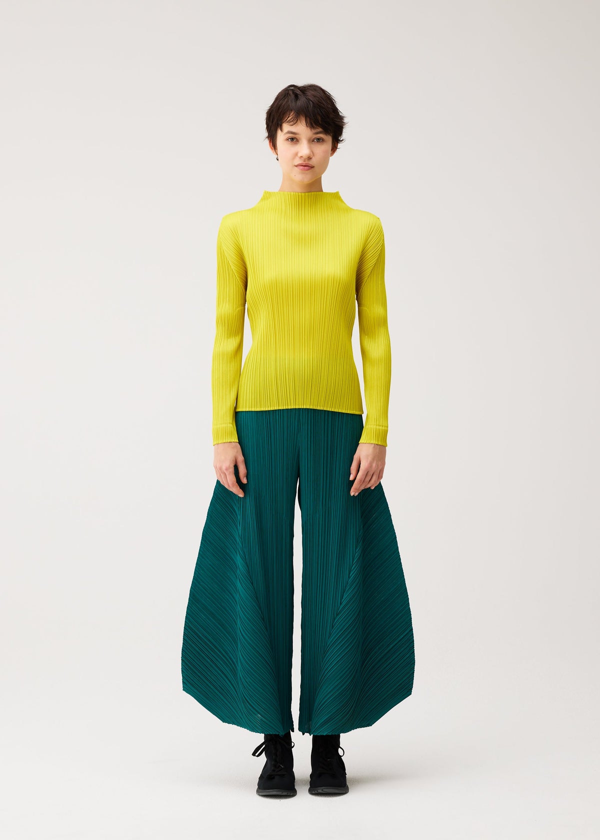 A model wears the PLEATS PLEASE ISSEY MIYAKE MONTHLY COLORS : OCTOBER monthly-colors-october-flared-trousers-dark-green.