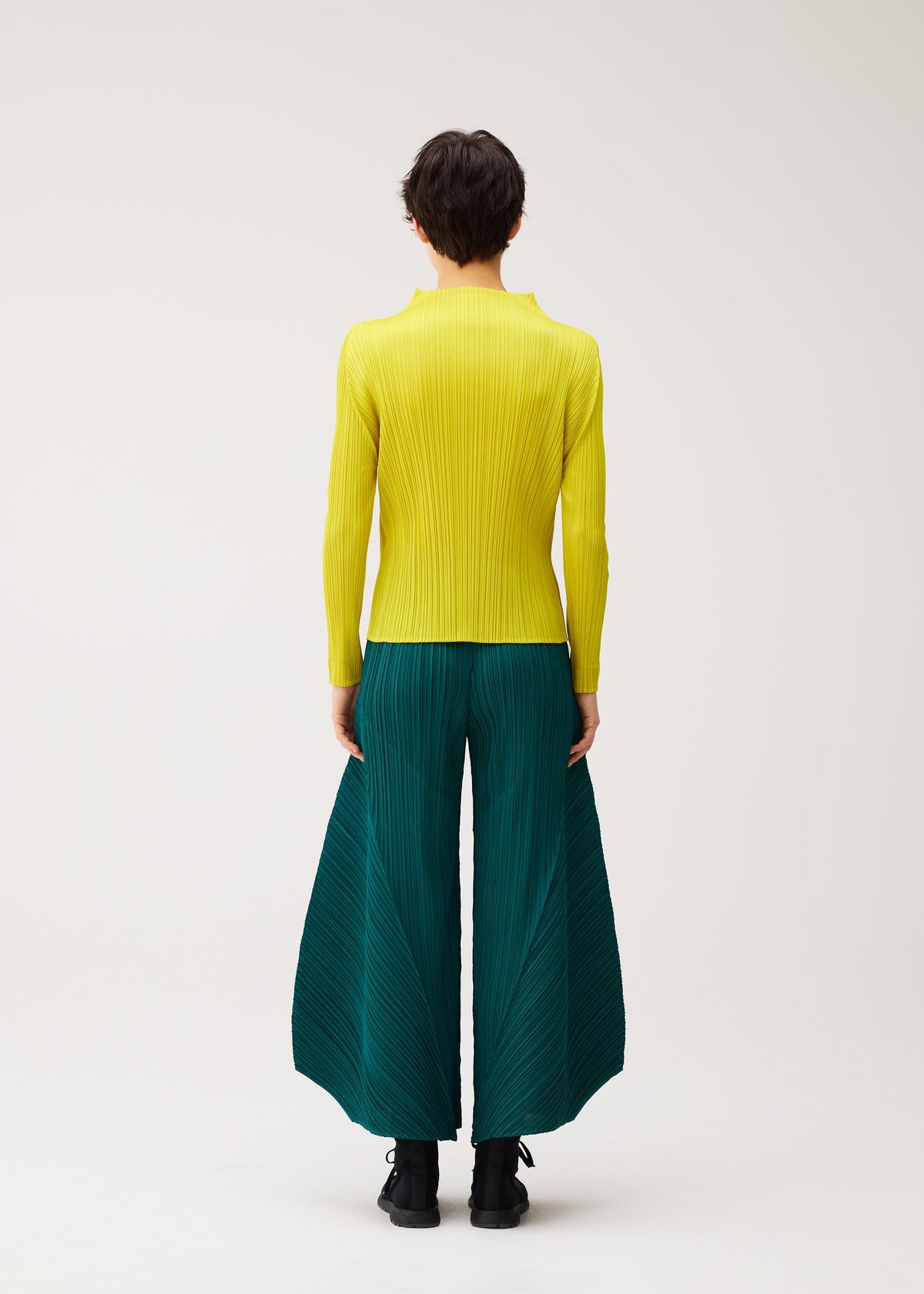 A model wears the PLEATS PLEASE ISSEY MIYAKE MONTHLY COLORS : OCTOBER monthly-colors-october-flared-trousers-green.