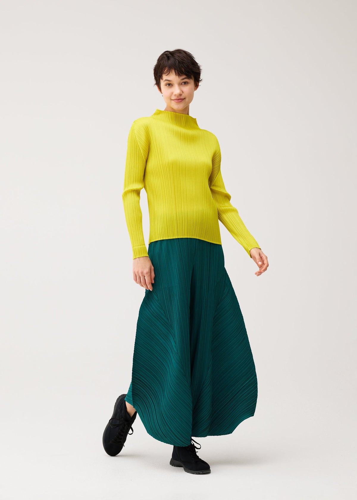 A model wears the PLEATS PLEASE ISSEY MIYAKE MONTHLY COLORS : OCTOBER monthly-colors-october-flared-trousers-dark-green.