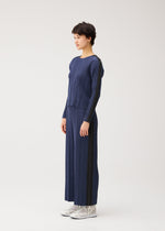 A model wears the PLEATS PLEASE ISSEY MIYAKE COTTON DENIM cotton-denim-trousers-dark-green.