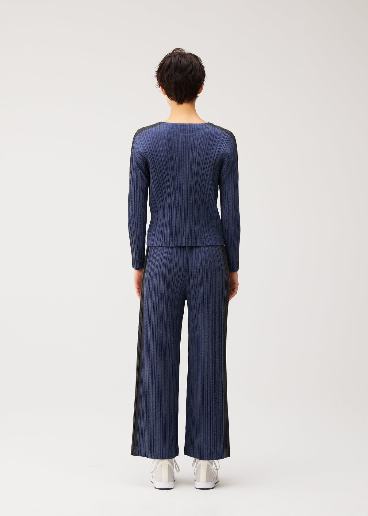 A model wears the PLEATS PLEASE ISSEY MIYAKE COTTON DENIM cotton-denim-trousers-navy-blue.