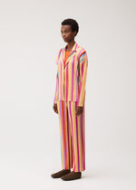 A model wears the PLEATS PLEASE ISSEY MIYAKE TAPE TAPE tape-tape-trousers-orange.