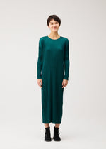 A model wears the PLEATS PLEASE ISSEY MIYAKE MONTHLY COLORS : OCTOBER monthly-colors-october-midi-dress-yellow-ochre.
