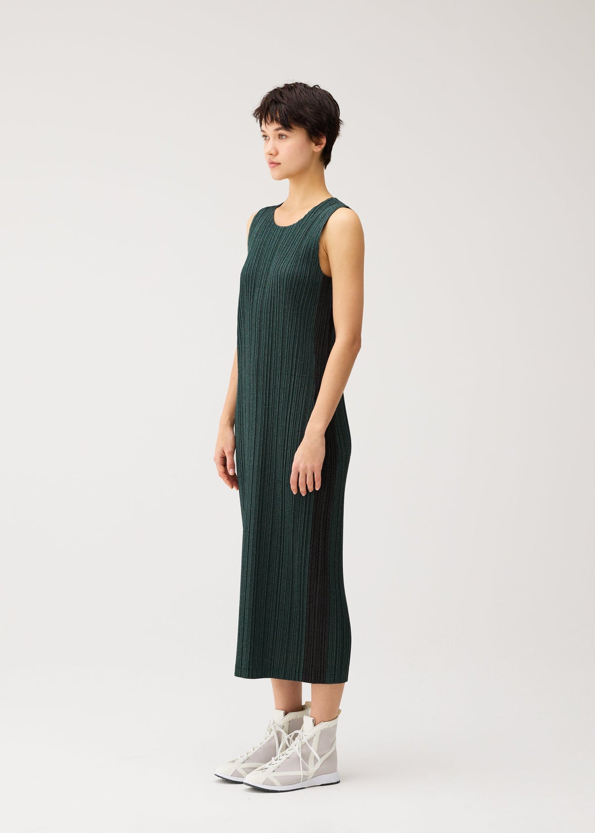 A model wears the PLEATS PLEASE ISSEY MIYAKE COTTON DENIM cotton-denim-dress-dark-green.