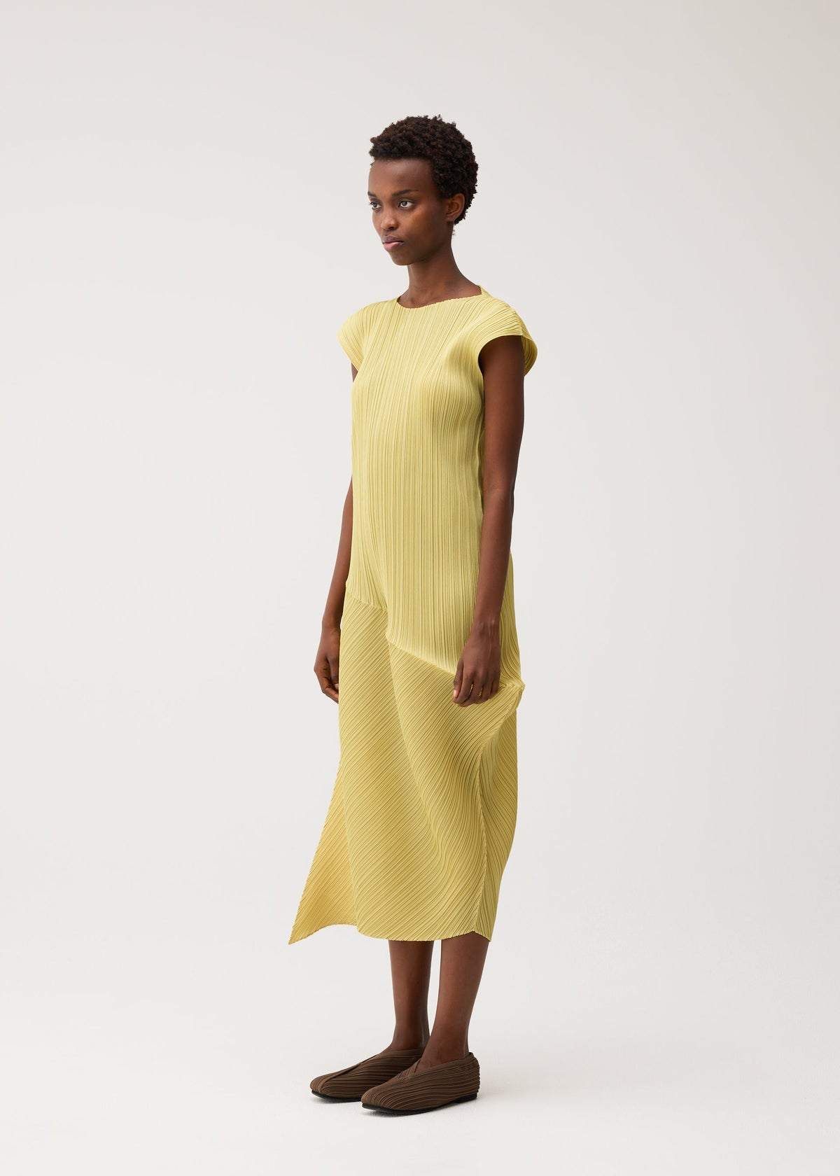 A model wears the PLEATS PLEASE ISSEY MIYAKE LEAP leap-dress-forest-green.
