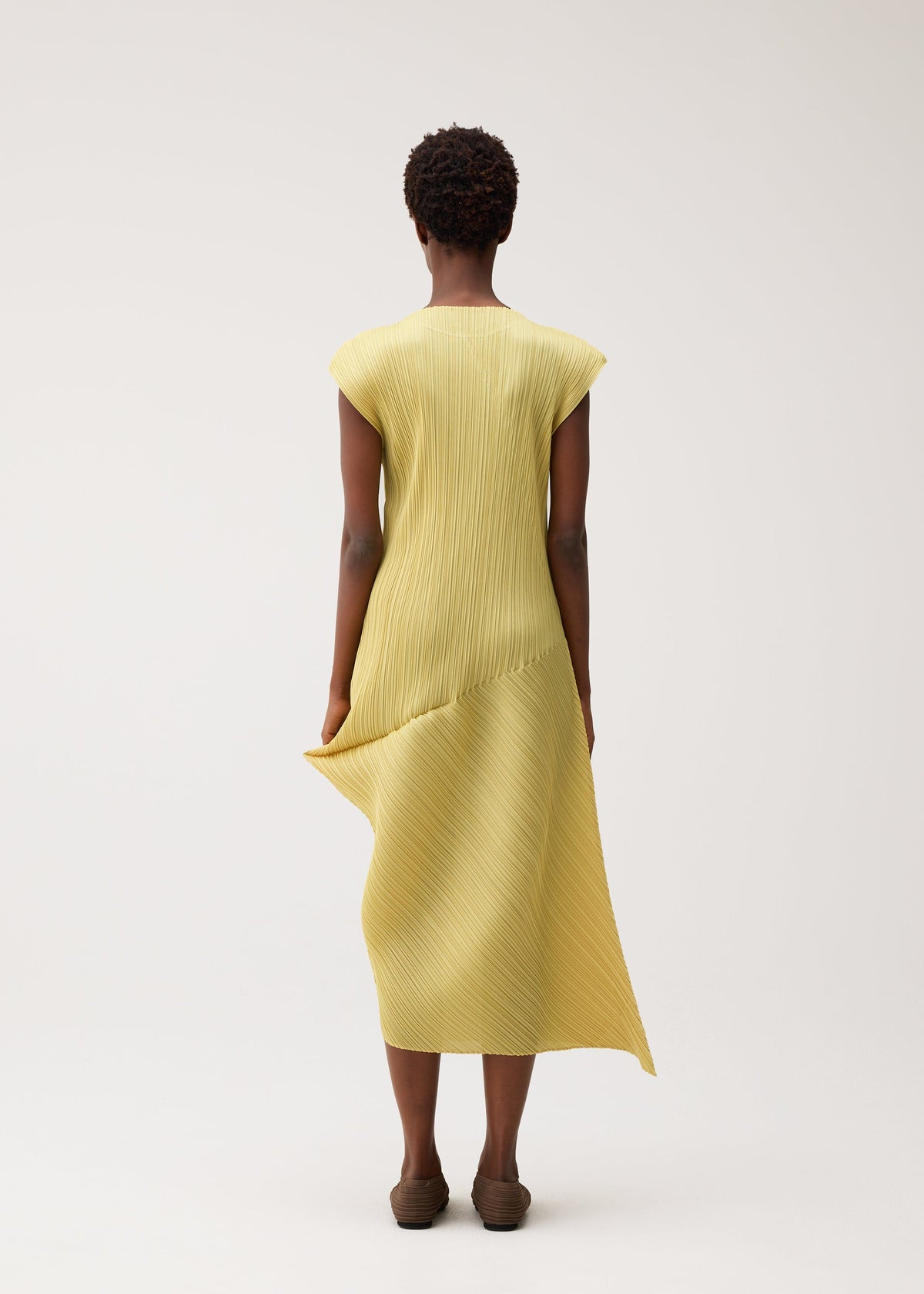 A model wears the PLEATS PLEASE ISSEY MIYAKE LEAP leap-dress-pale-yellow.