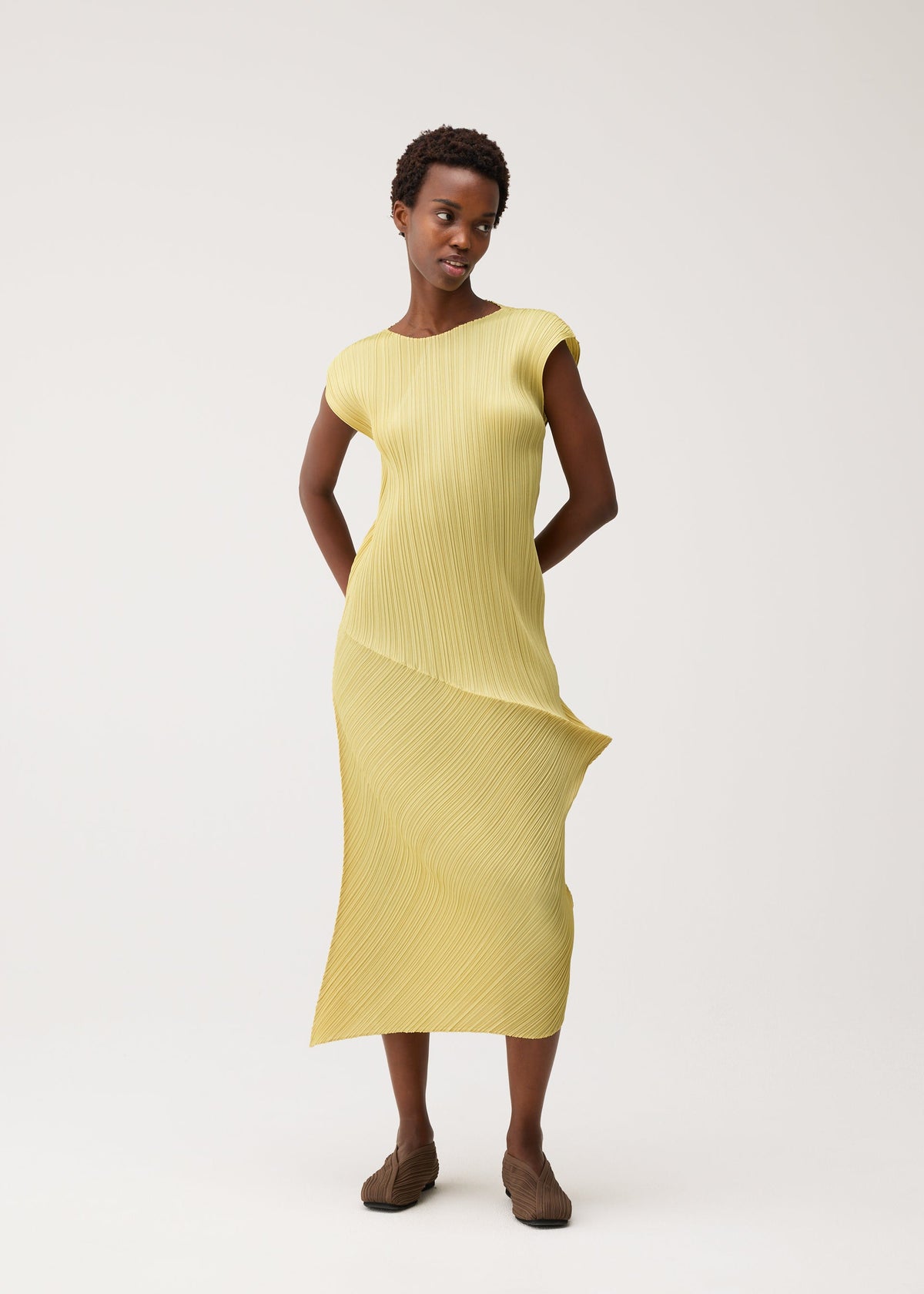 A model wears the PLEATS PLEASE ISSEY MIYAKE LEAP leap-dress-pale-yellow.