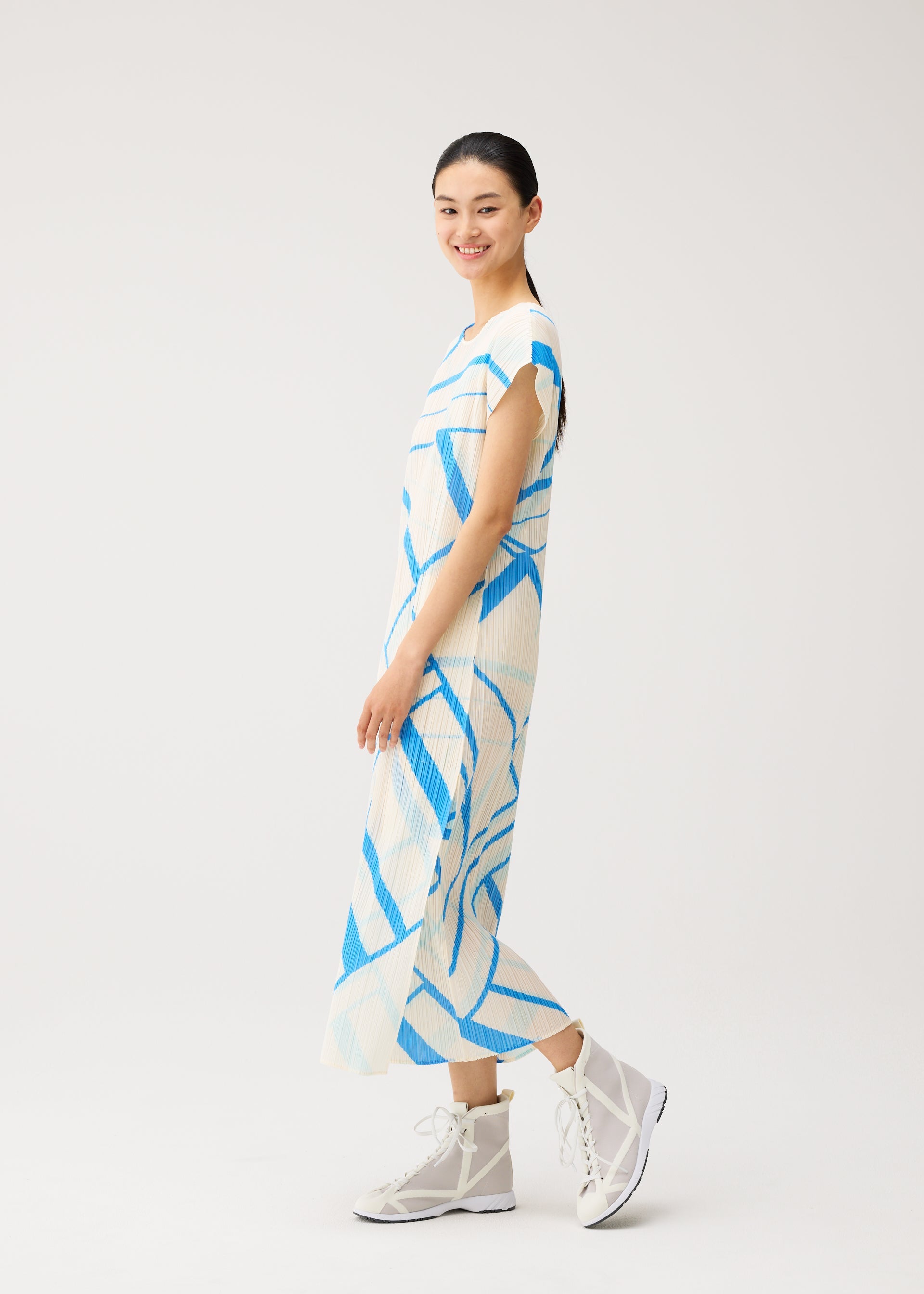 A model wears the PLEATS PLEASE ISSEY MIYAKE FOLD LINE fold-line-dress-off-white.