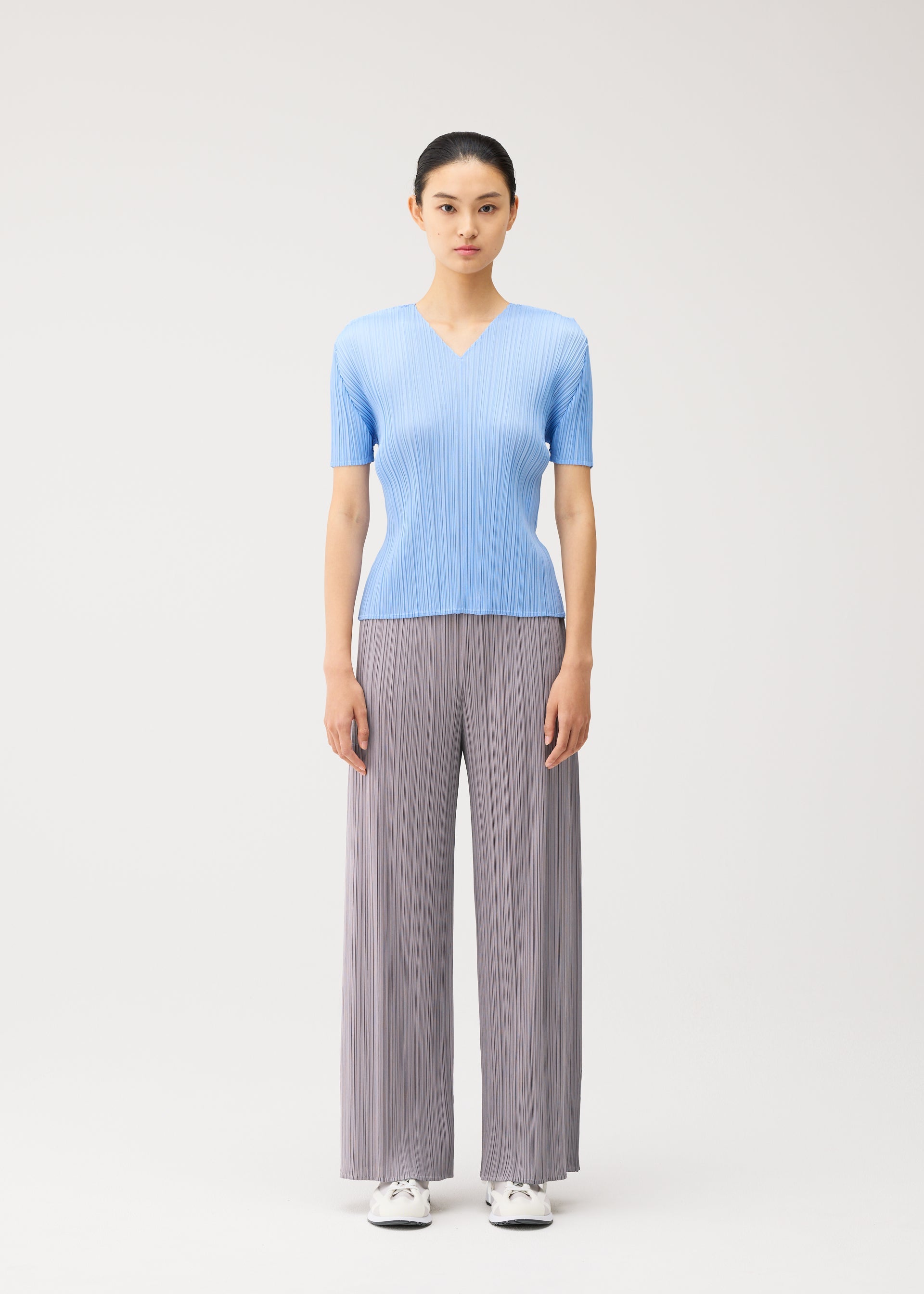 A model wears the PLEATS PLEASE ISSEY MIYAKE MONTHLY COLORS : AUGUST monthly-colors-august-v-neck-top-greyish-green.