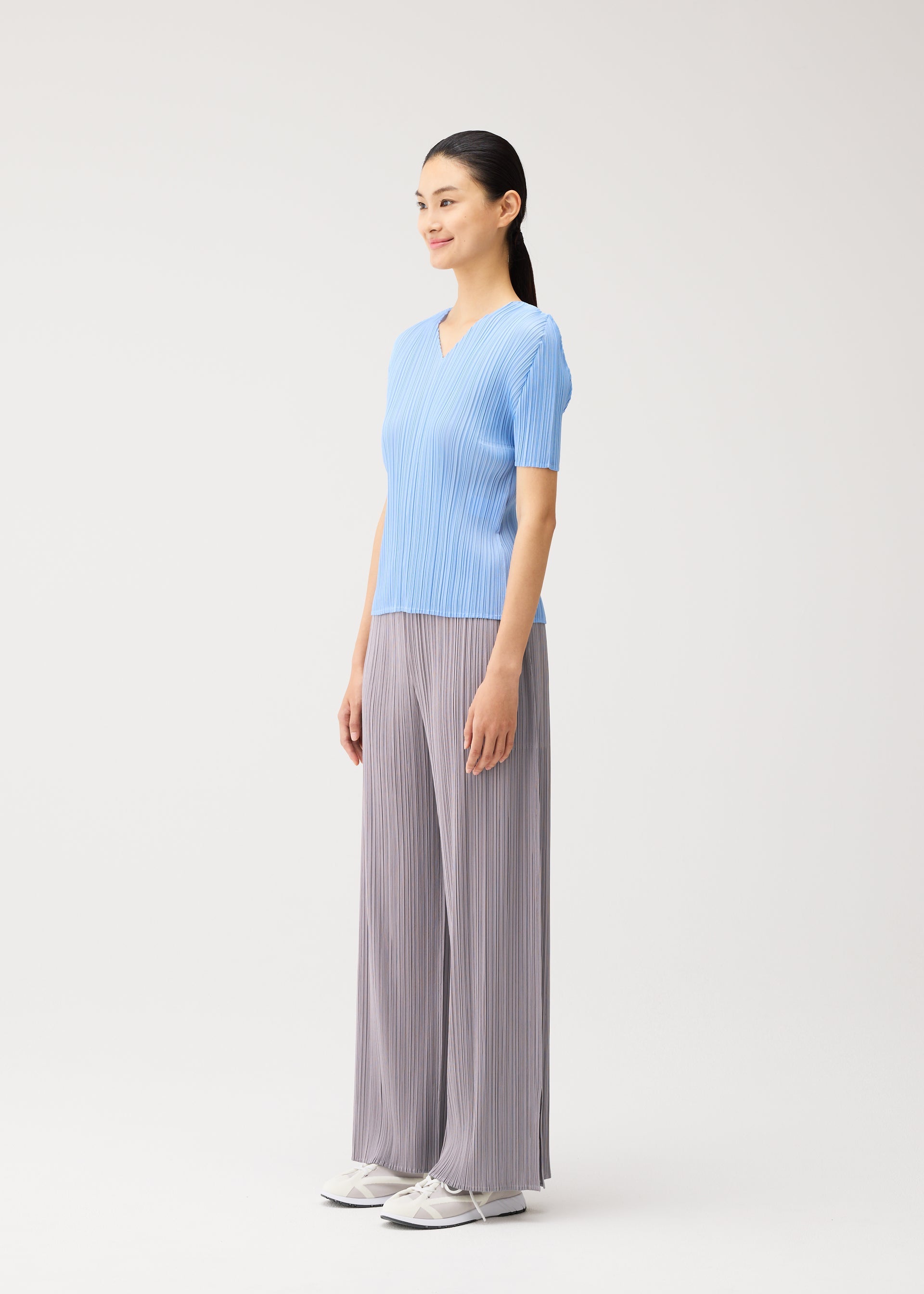 A model wears the PLEATS PLEASE ISSEY MIYAKE MONTHLY COLORS : AUGUST monthly-colors-august-v-neck-top-light-blue.
