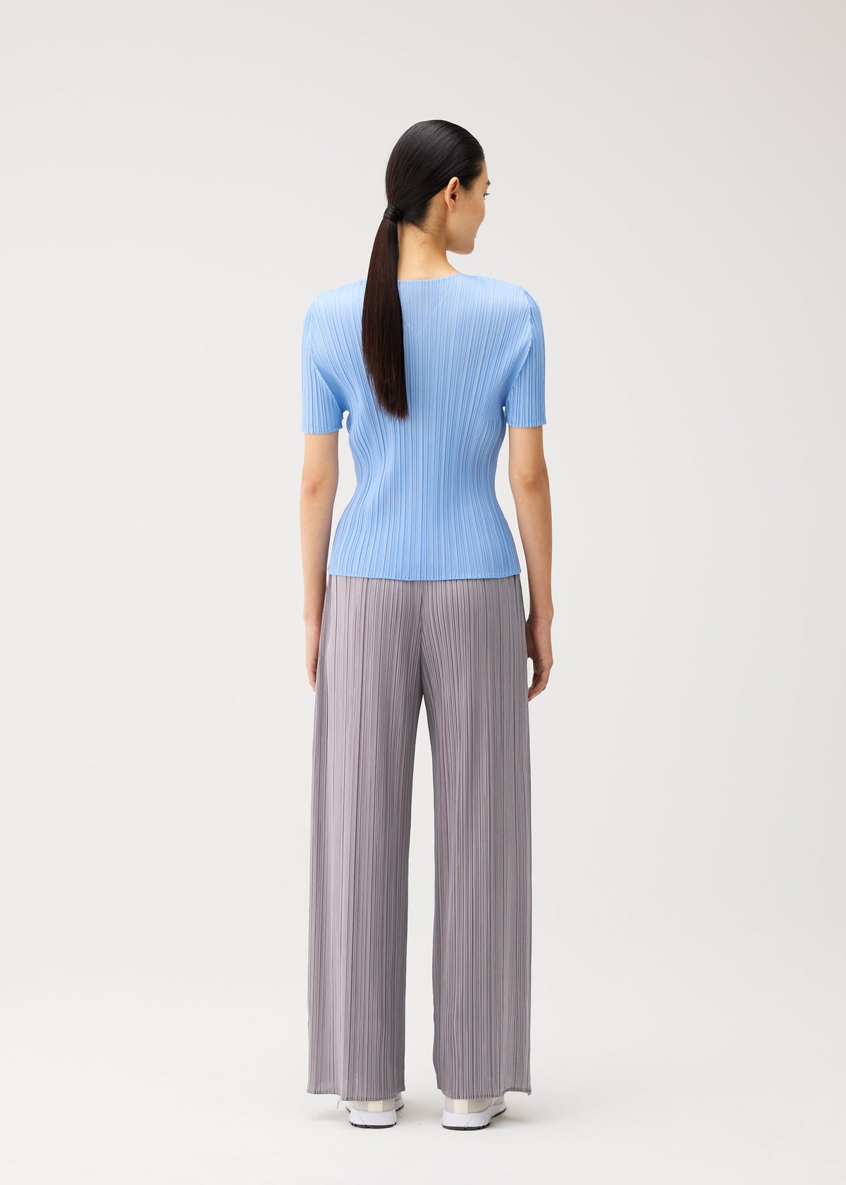 A model wears the PLEATS PLEASE ISSEY MIYAKE MONTHLY COLORS : AUGUST monthly-colors-august-v-neck-top-light-blue.