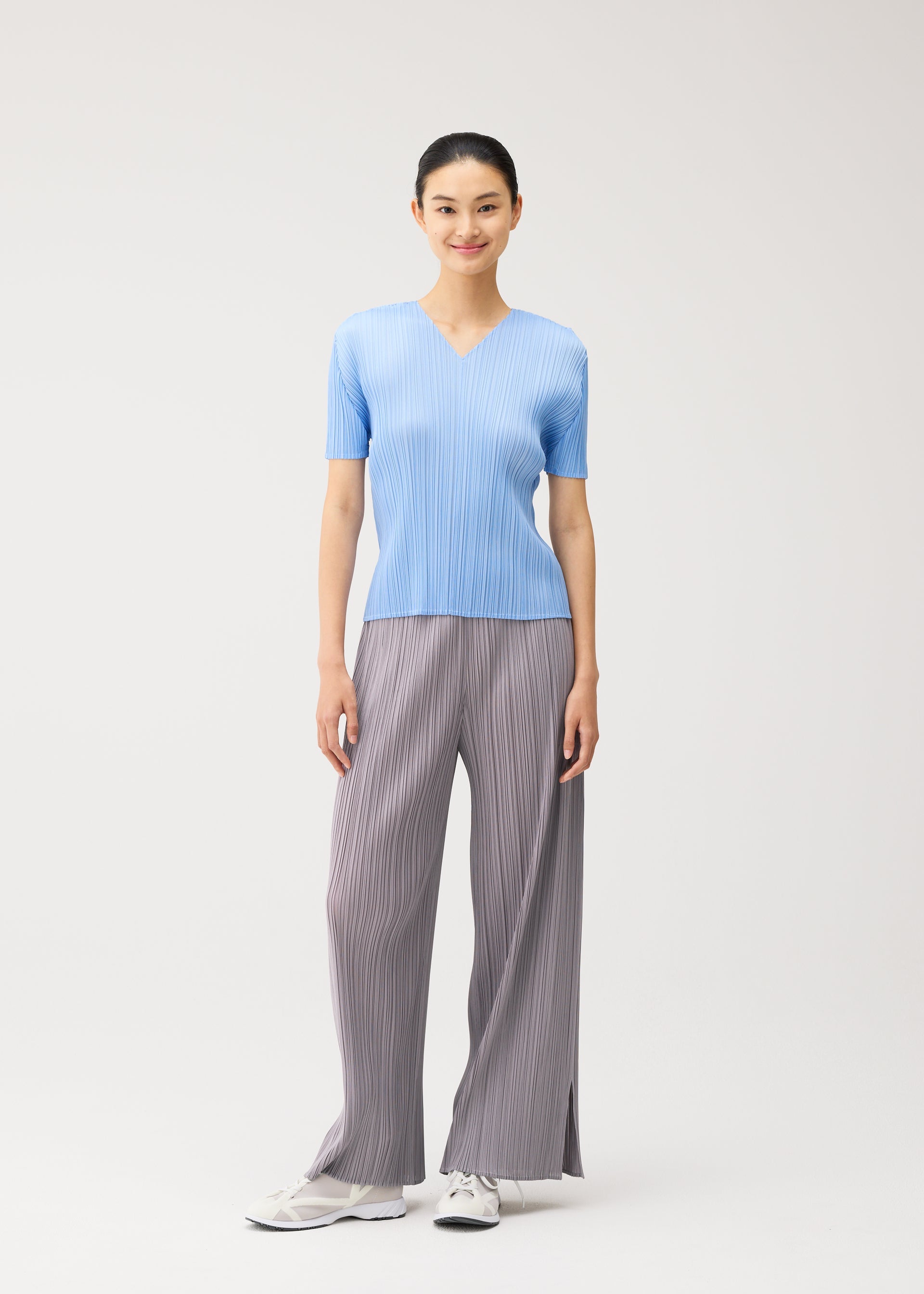 A model wears the PLEATS PLEASE ISSEY MIYAKE MONTHLY COLORS : AUGUST monthly-colors-august-v-neck-top-light-blue.